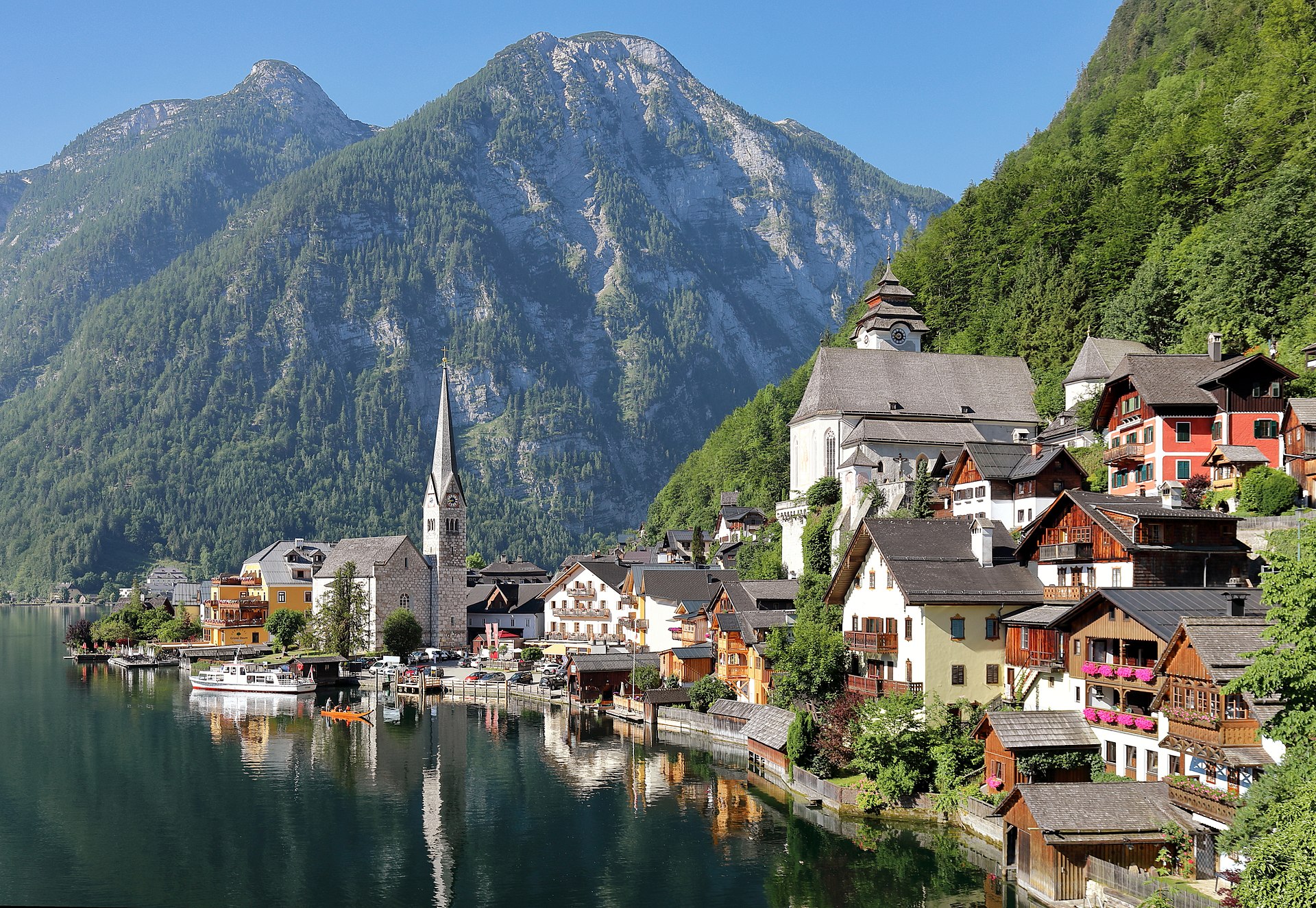 Hallstatt village center with pastel-colored houses and the church spire clustered along the shore of the Hallstaettersee backed by Dachstein mountains