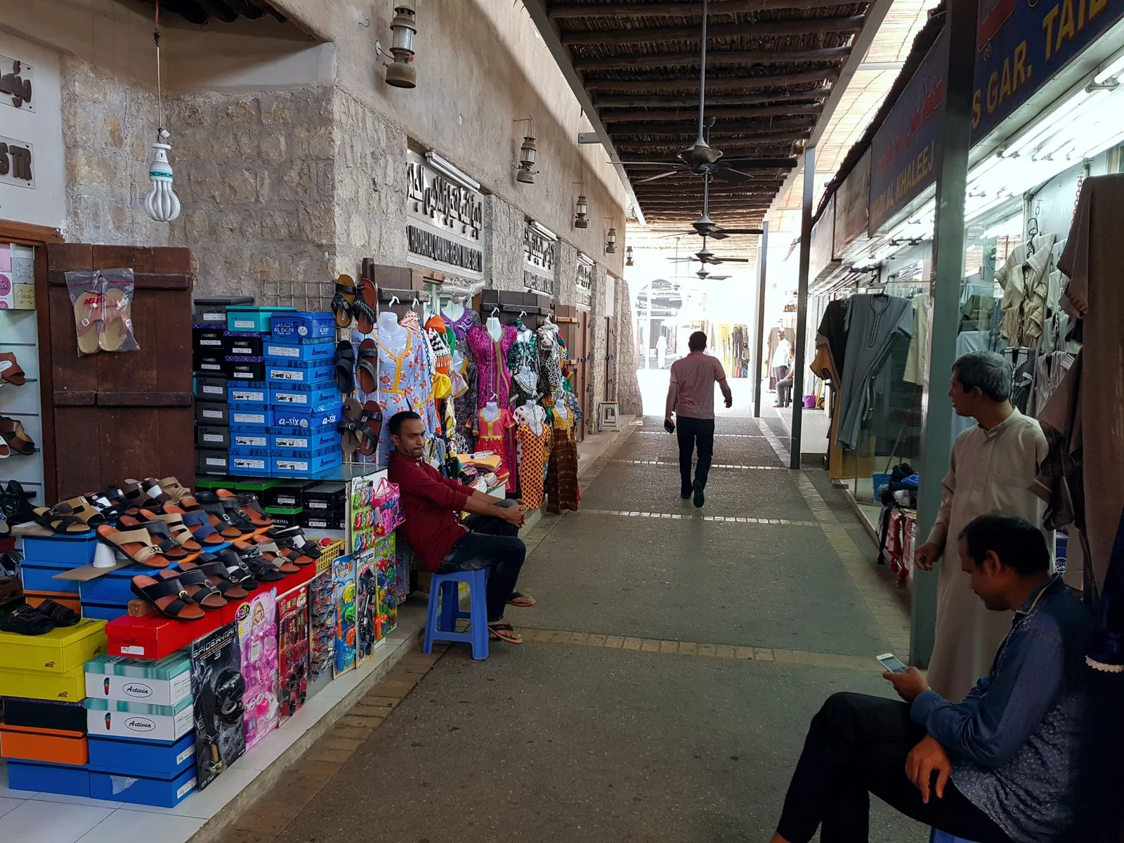 Covered market lane lined with shoe and clothing stalls in the Heart of Sharjah heritage area