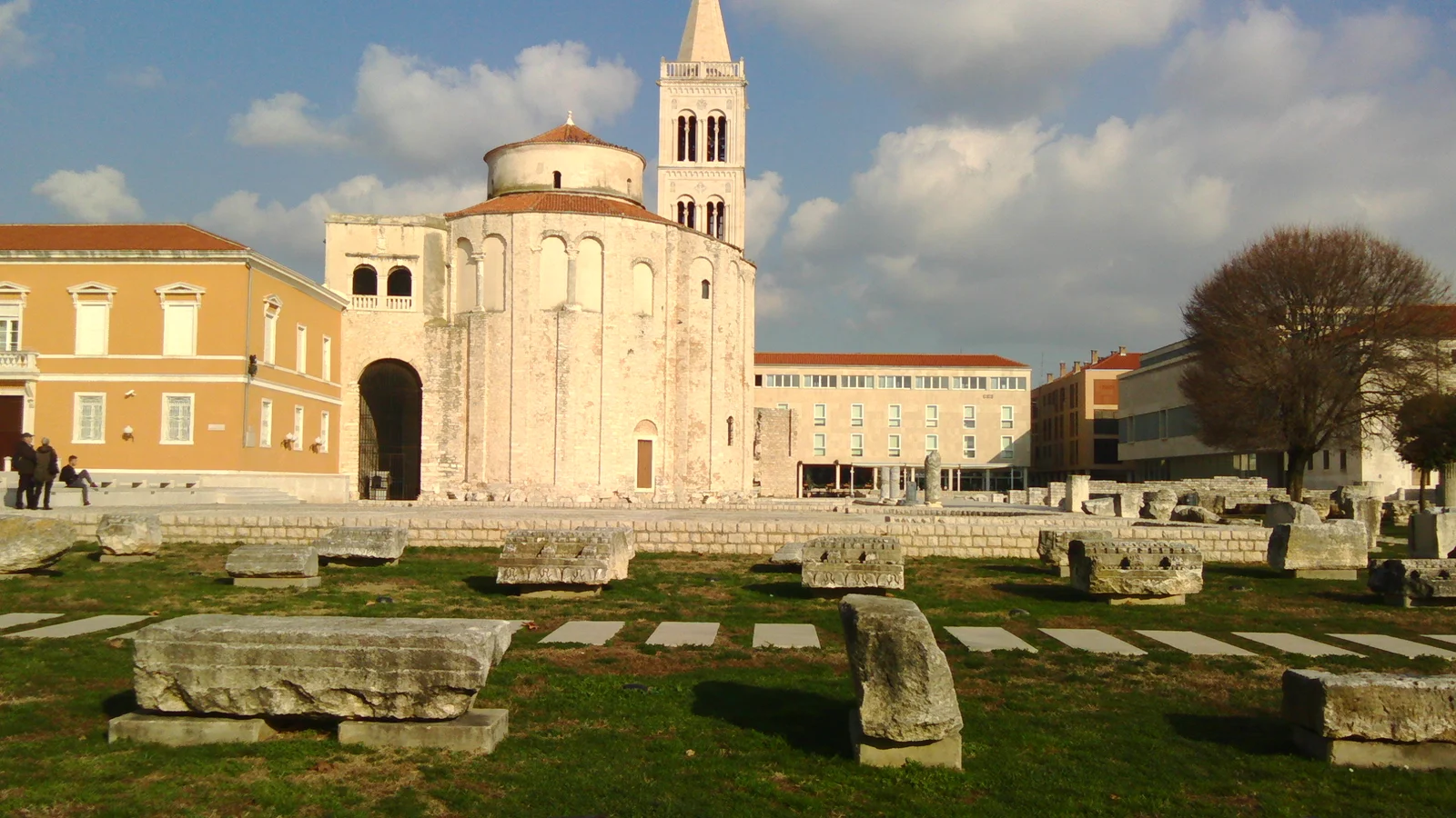 The open paved expanse of Zadar's Roman Forum with its surviving monumental column standing against the old-town skyline