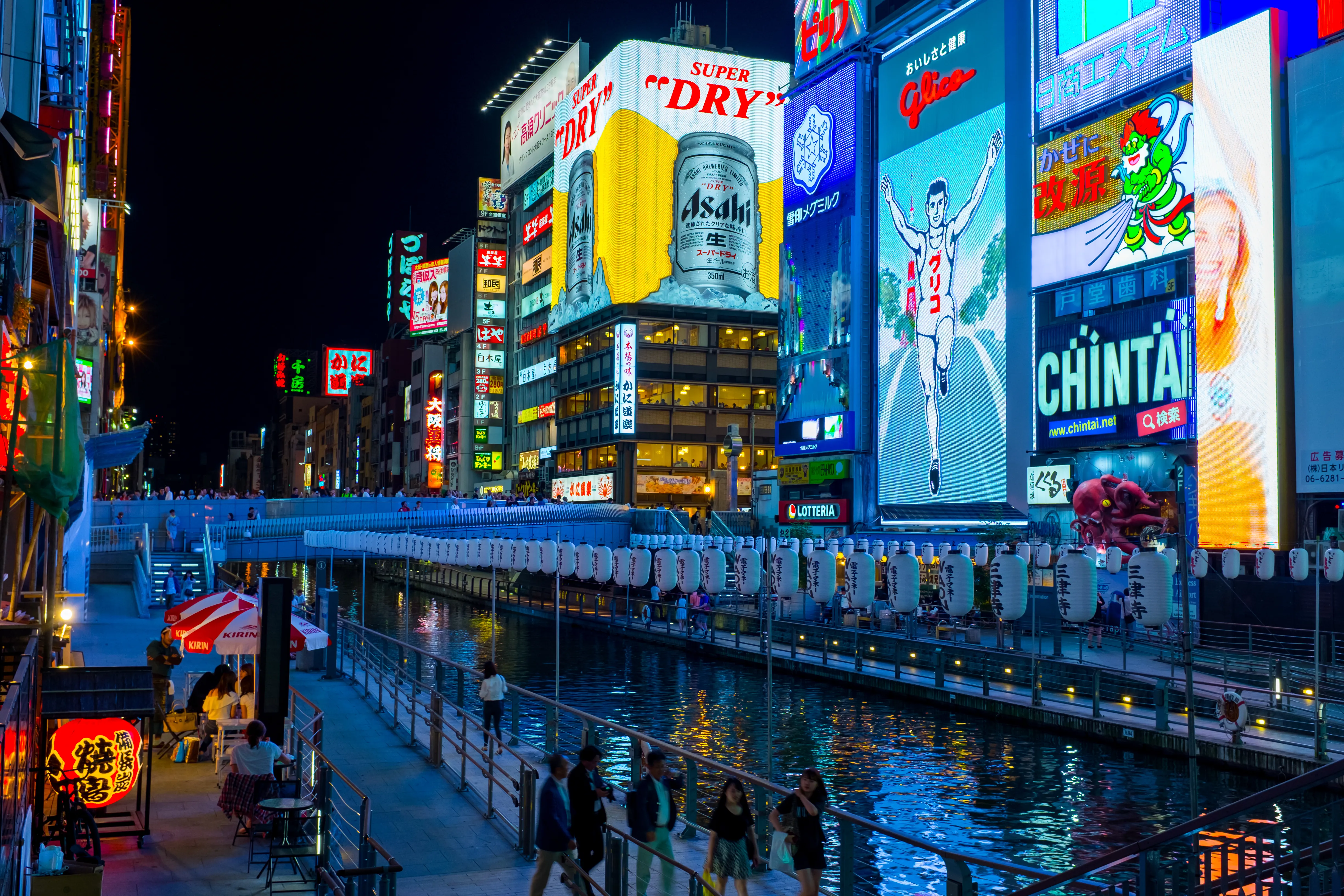 Glowing neon billboards reflected in the Dotonbori canal at night in Osaka
