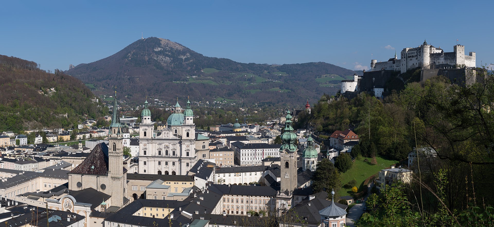 Panoramic view of Salzburg's old town with the Hohensalzburg Fortress on the hilltop, baroque church domes, and the Salzach River flowing through the city