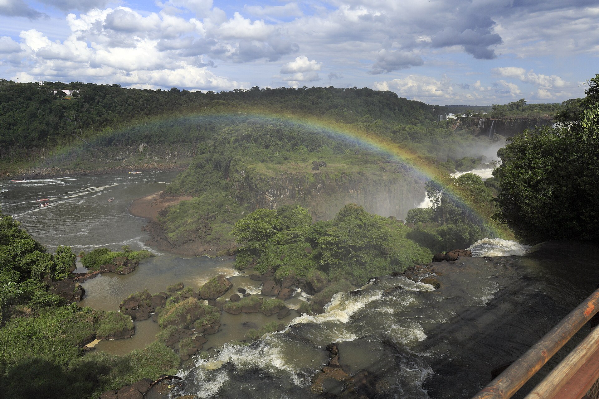 Isla San Martin surrounded by cascading waterfalls and rainbow at Iguazu Falls