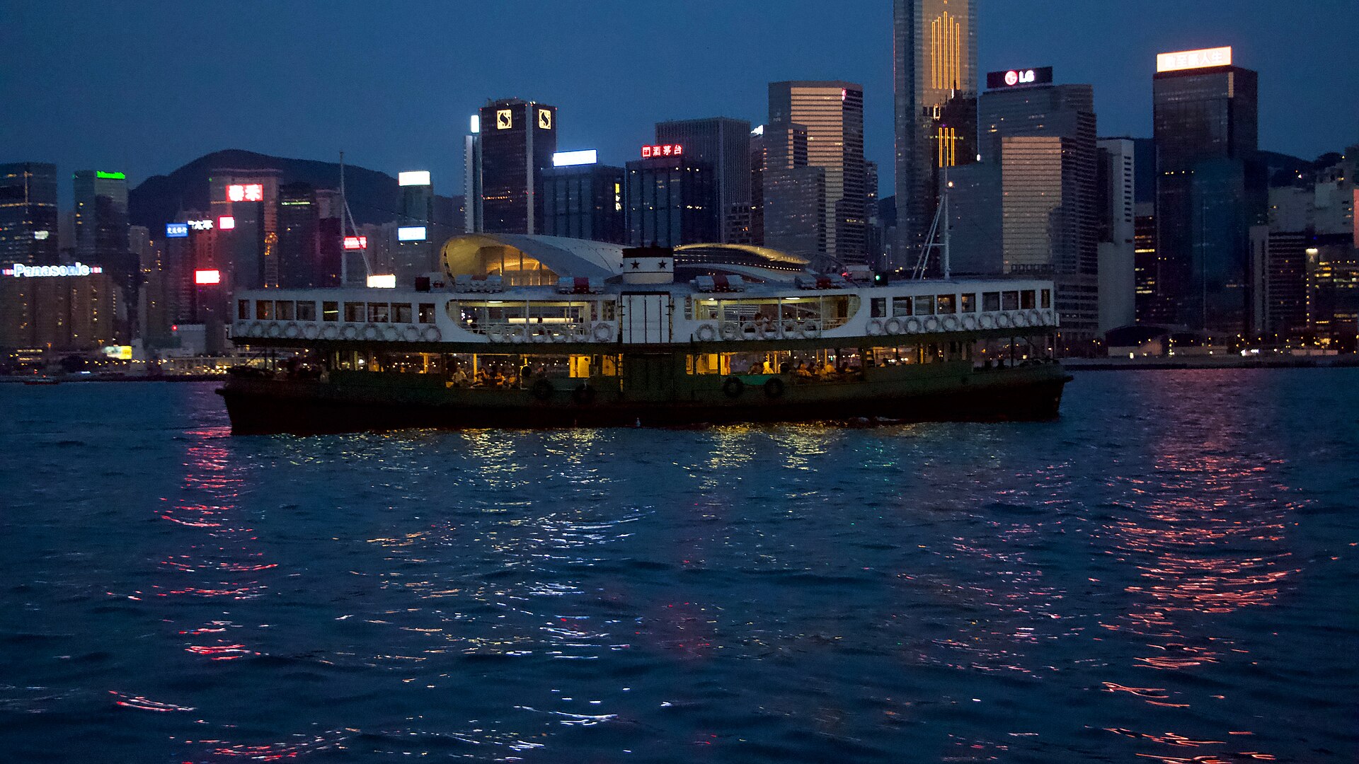 Star Ferry crossing Victoria Harbour at night with illuminated Hong Kong skyline