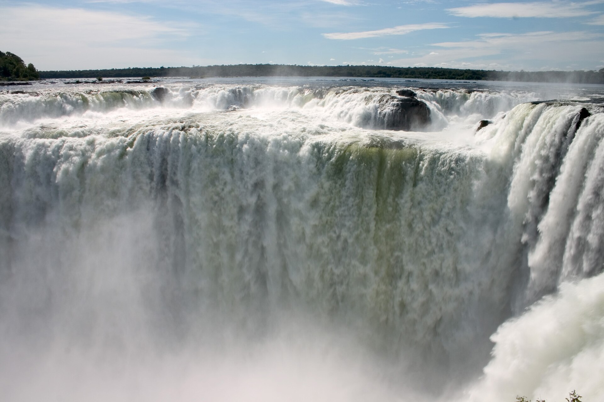The thundering Devil's Throat waterfall at Iguazu Falls with massive water curtains plunging into a misty chasm