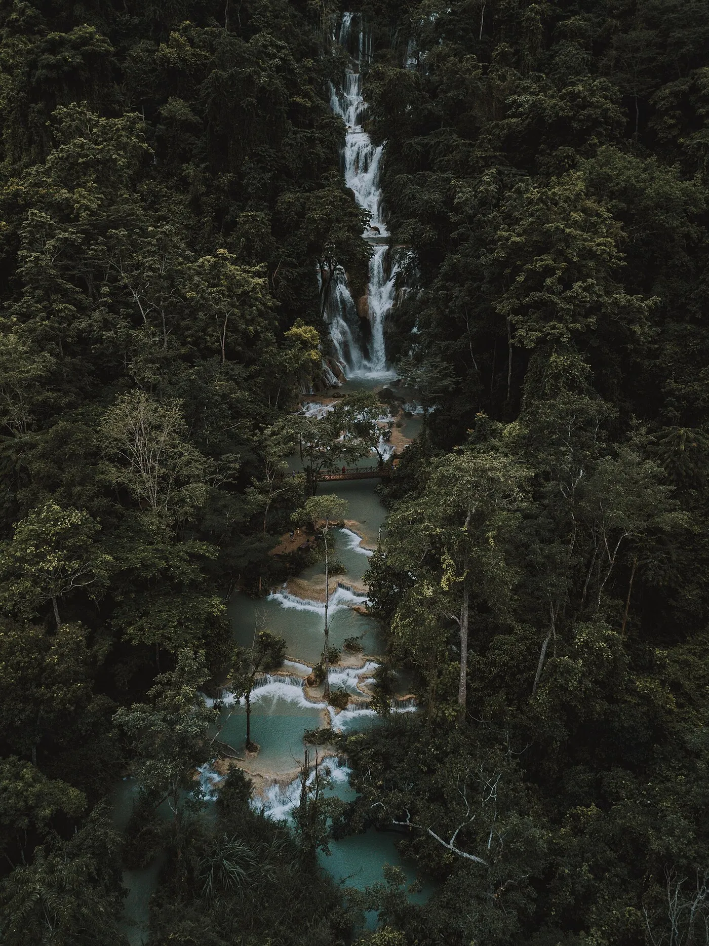 Turquoise tiered pools and waterfall cascading through jungle at Kuang Si near Luang Prabang, Laos