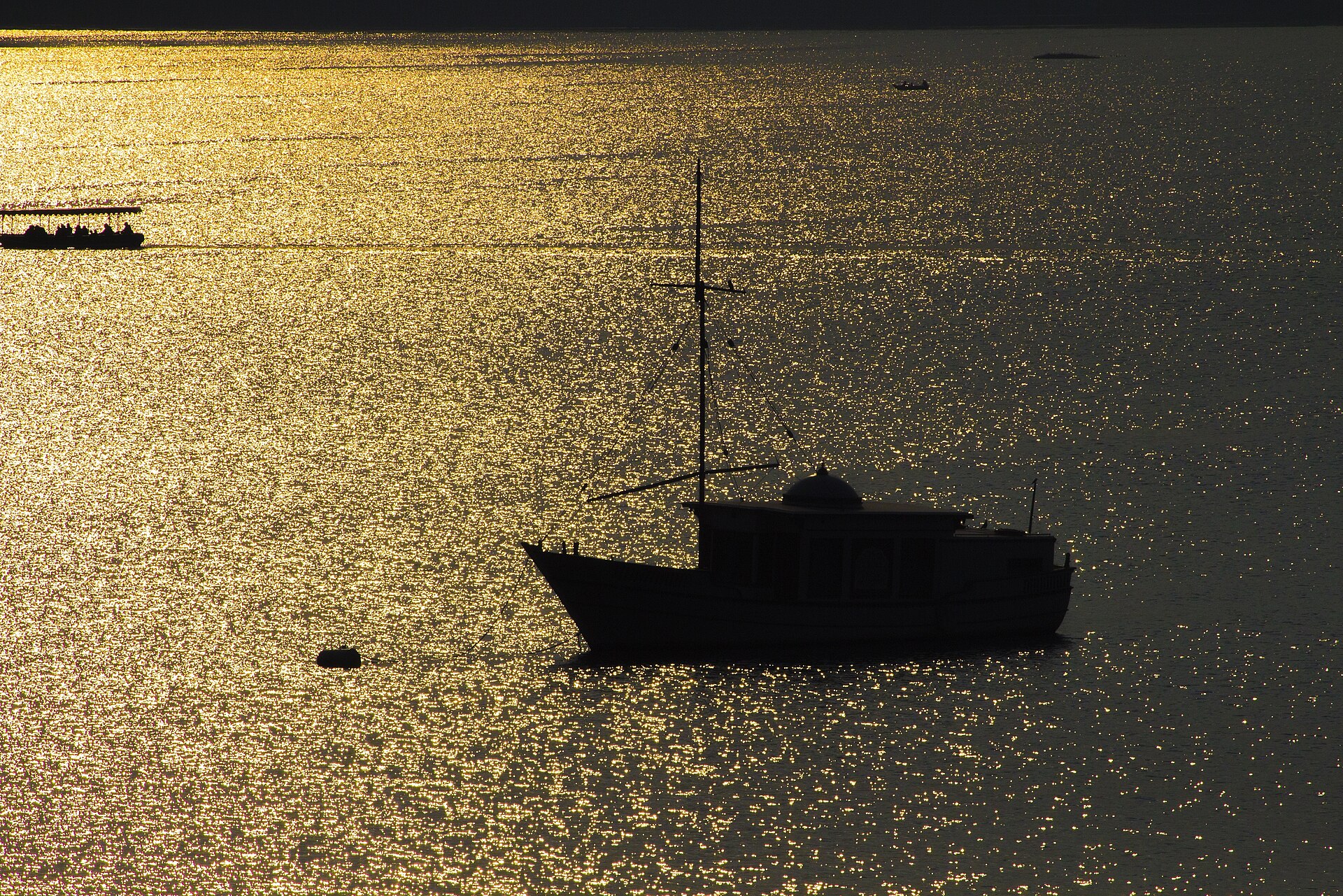 Boat silhouette on Lake Pichola at sunset with palace reflections in Udaipur