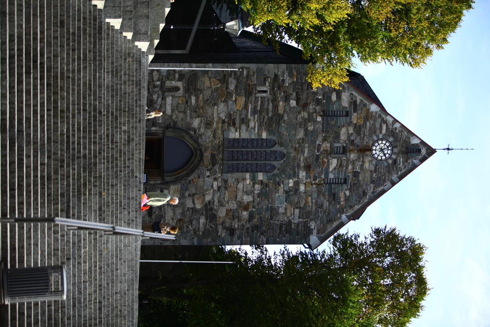 The stone west gable of Stavanger Cathedral with a round clock and tall pointed window, above a broad flight of steps