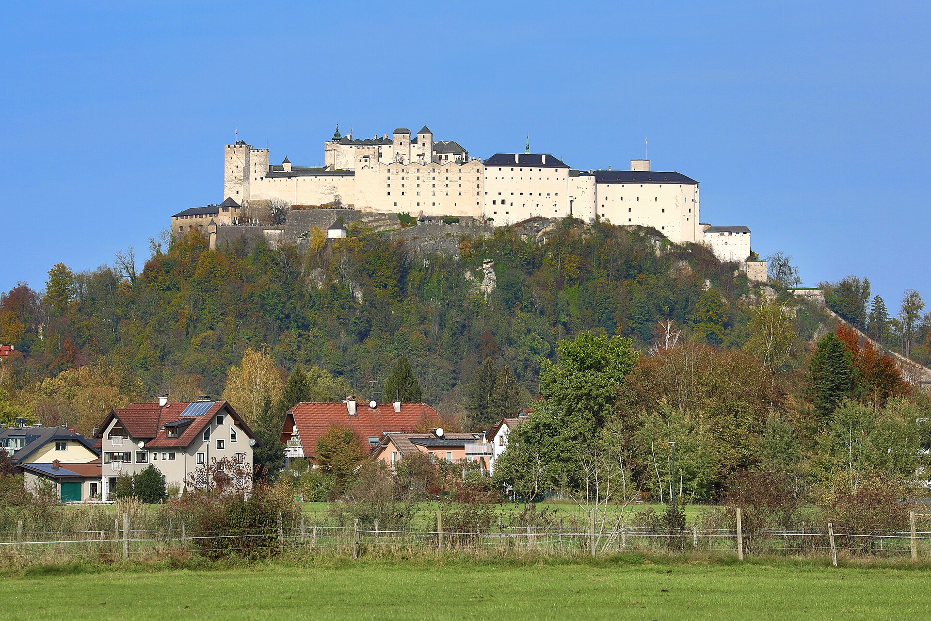 Hohensalzburg Fortress seen from below with its massive white walls and towers perched on the Festungsberg hill above Salzburg's old town