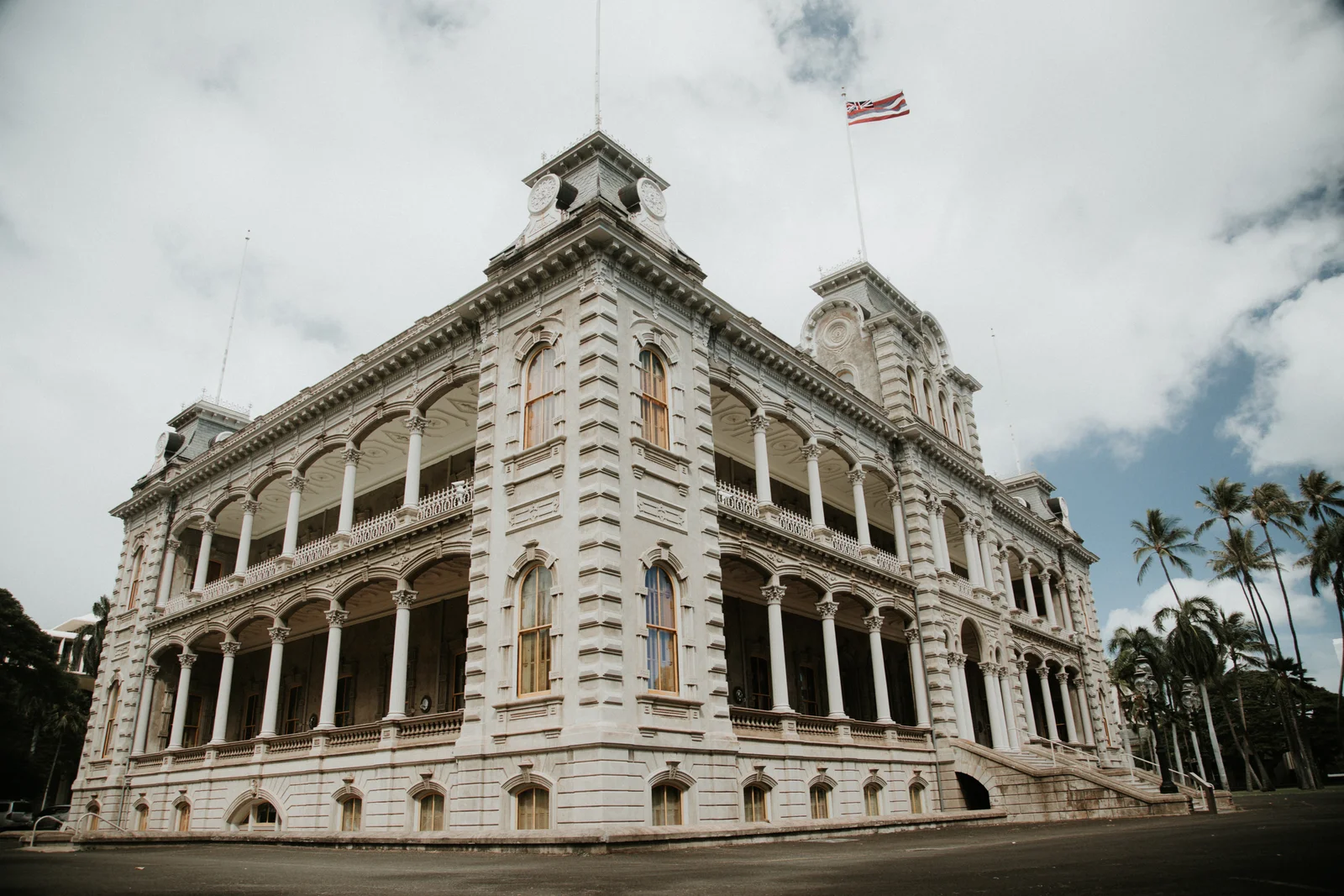 Corner view of Iolani Palace showing its two tiers of columned verandas and a corner tower