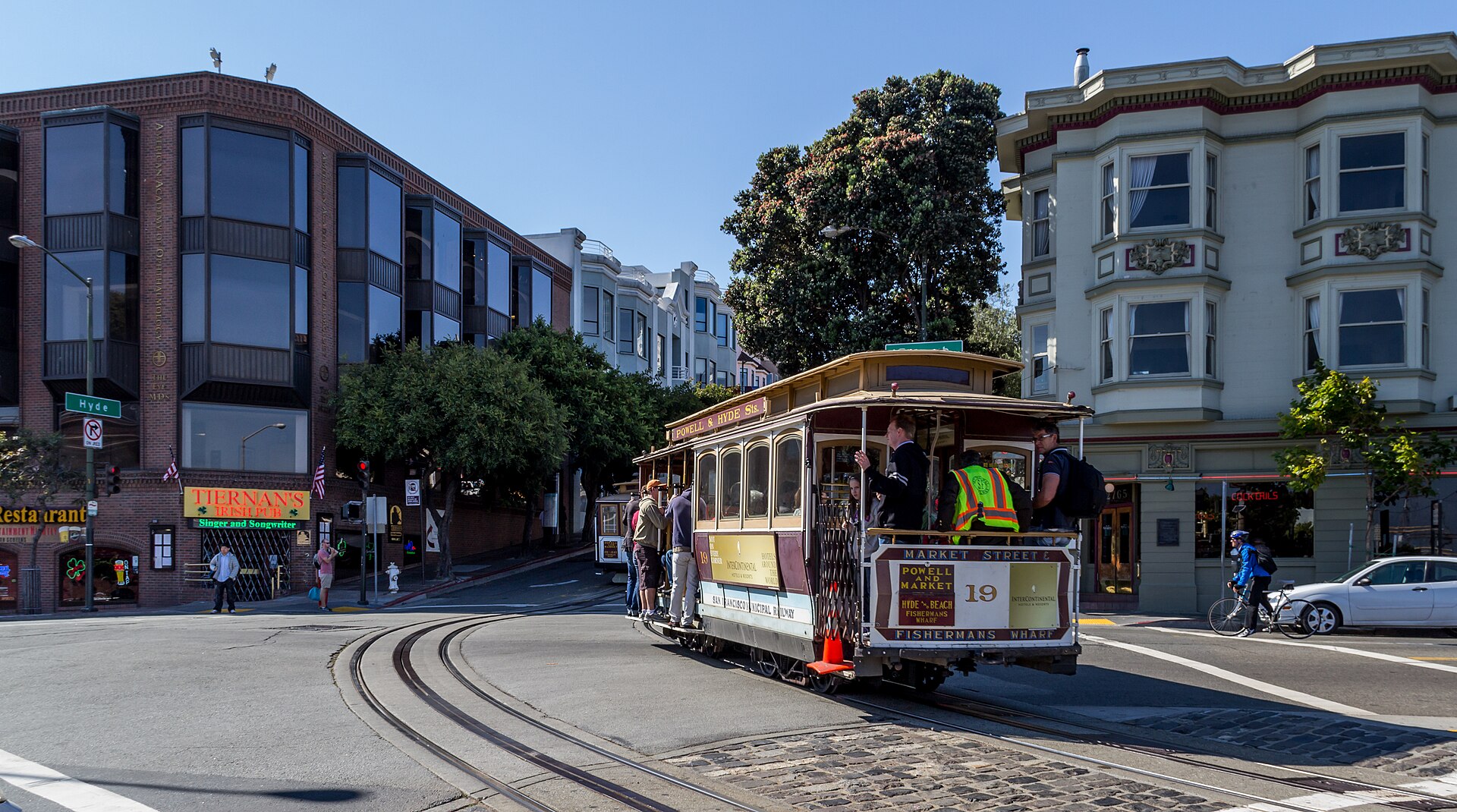 A San Francisco cable car climbing a hill on a sunny day