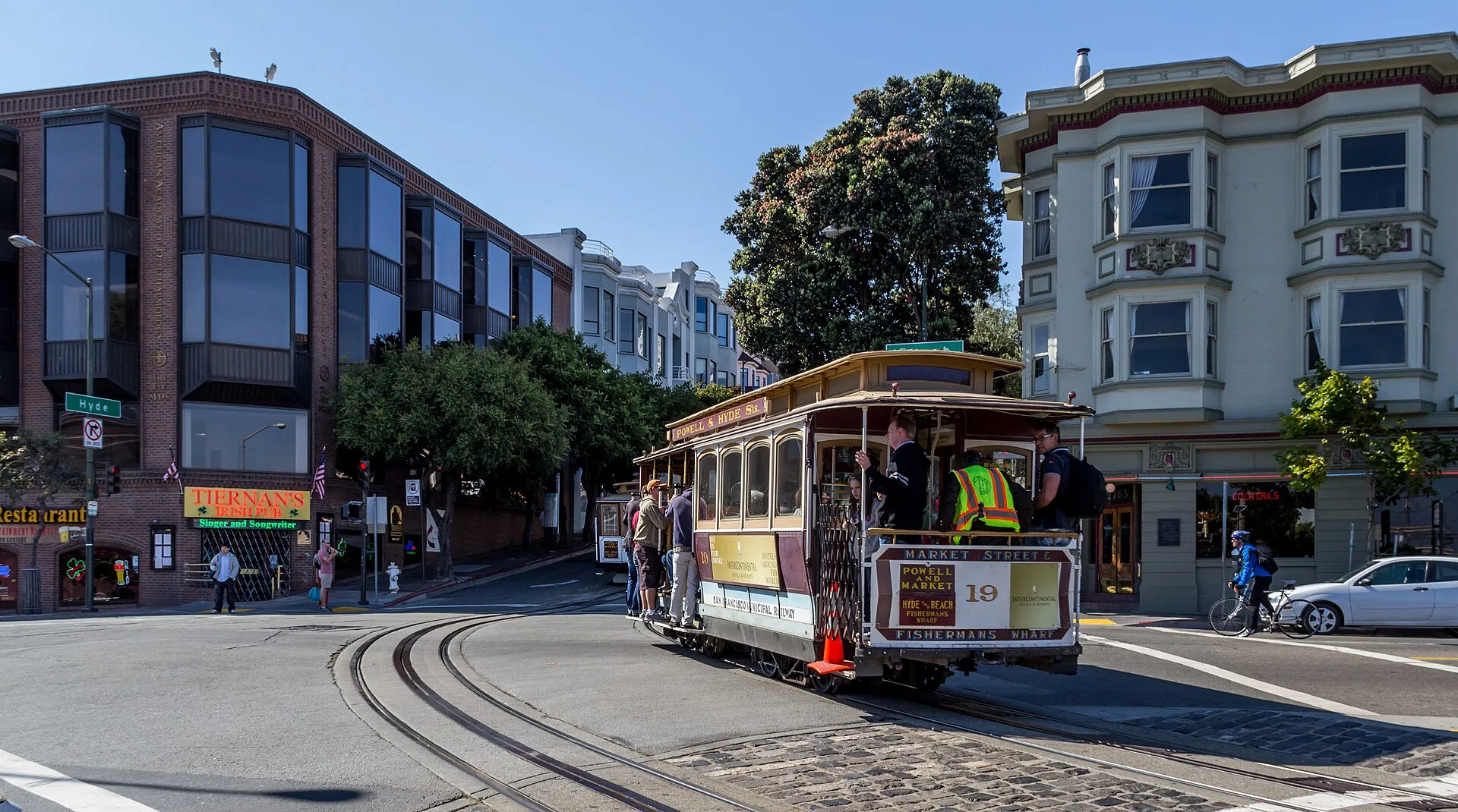 A San Francisco cable car climbing a hill on a sunny day