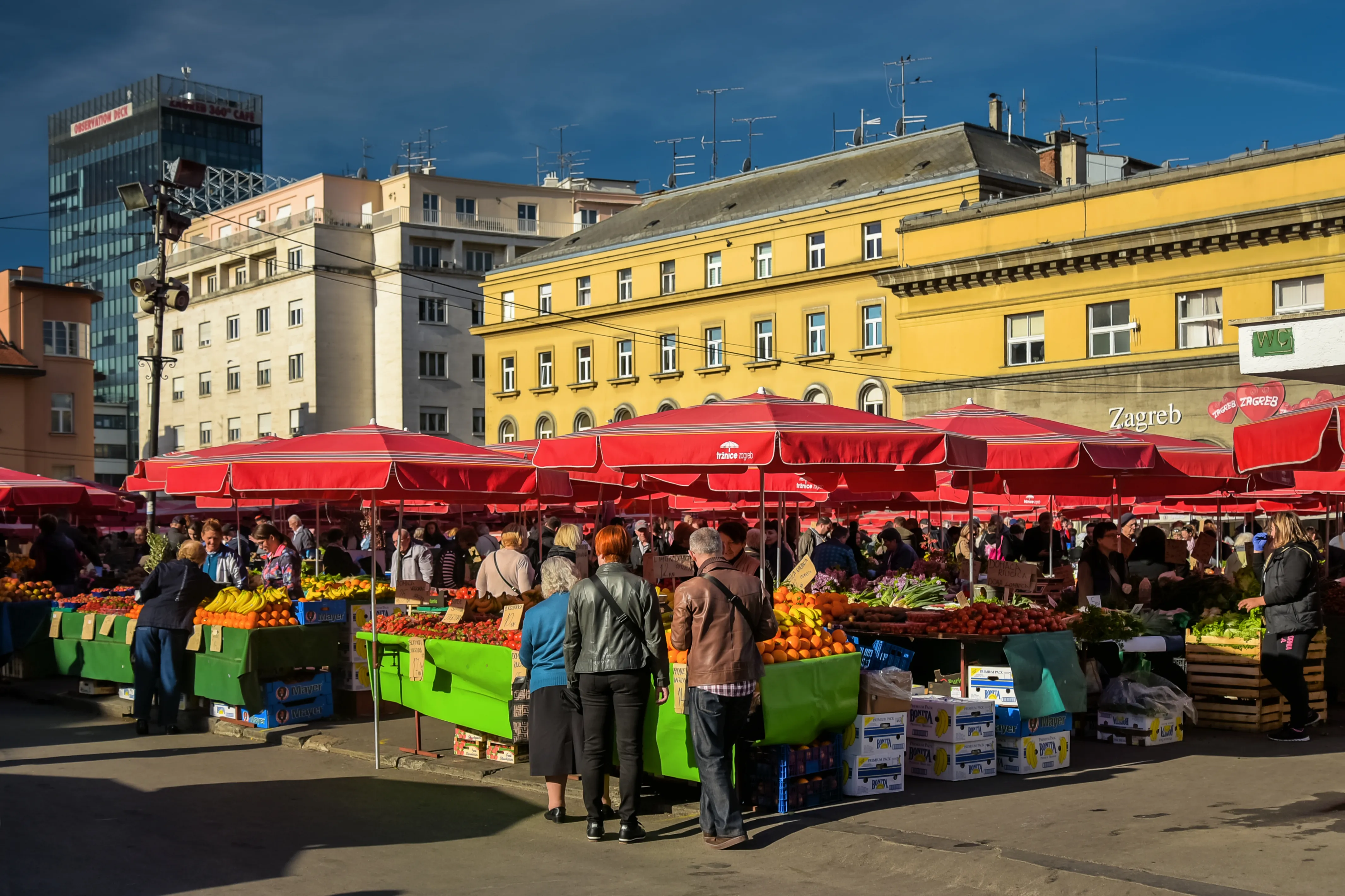 Rows of red parasols shading produce stalls at Dolac open-air market in central Zagreb