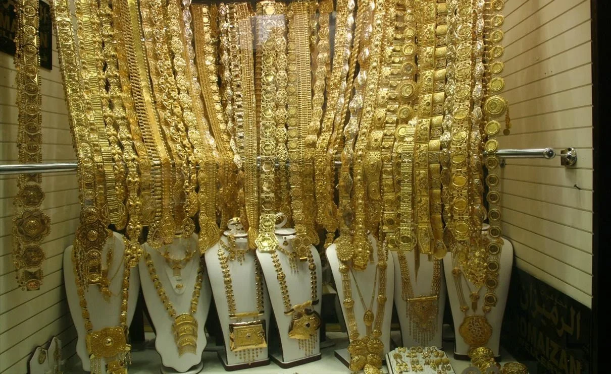 Gold necklaces and bangles displayed behind a jeweller's shop window at the Dubai Gold Souk