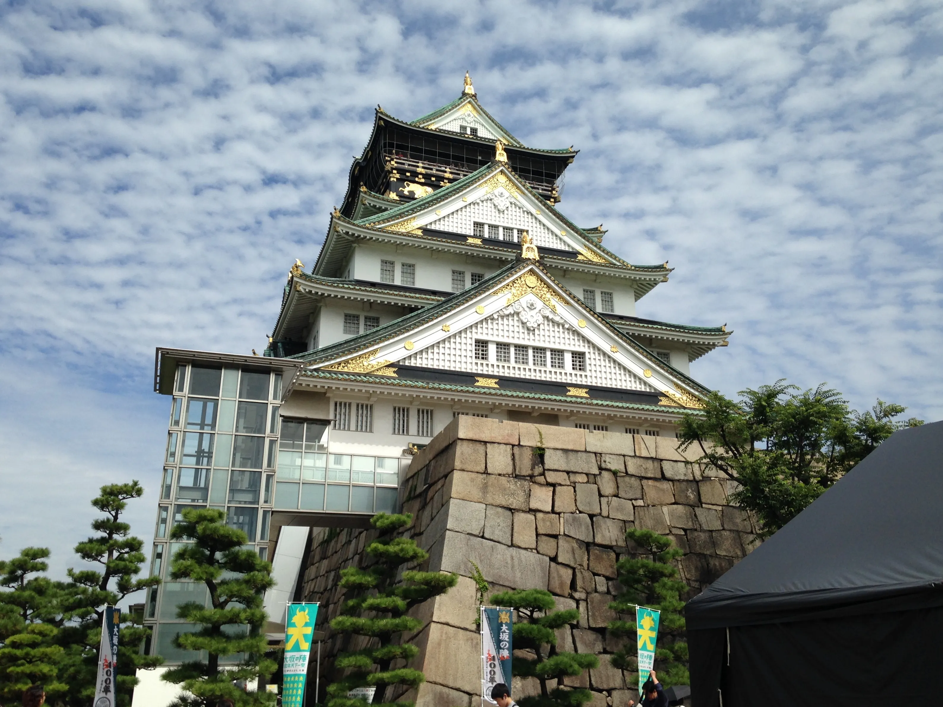 The green-roofed white keep of Osaka Castle with gold trim rising above its stone base