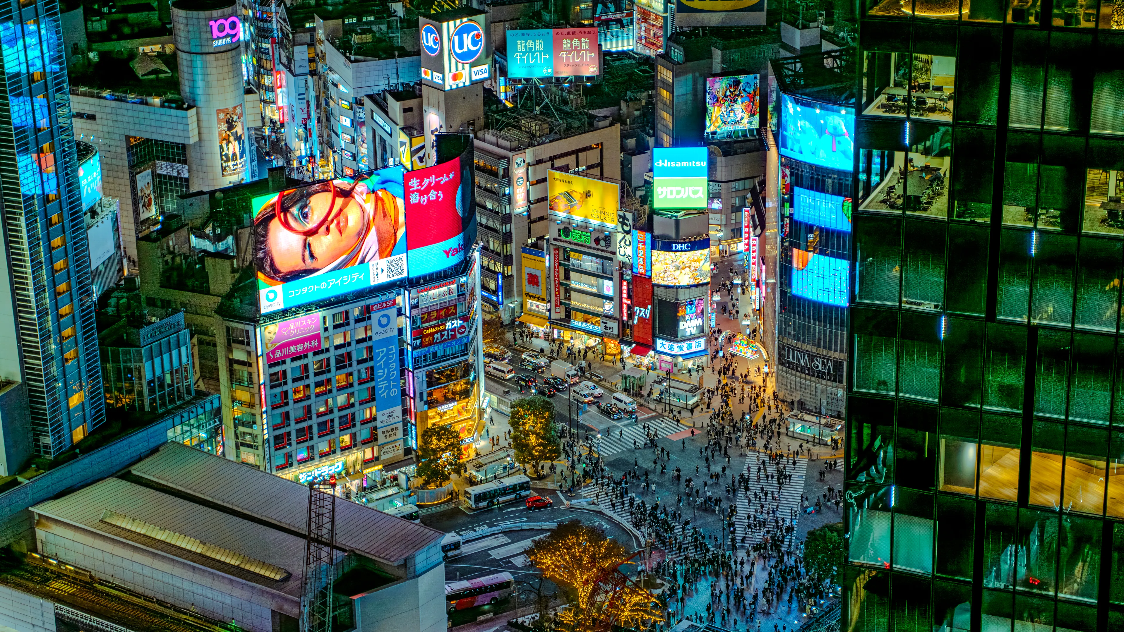 An aerial view of crowds streaming across the Shibuya scramble crossing from all directions