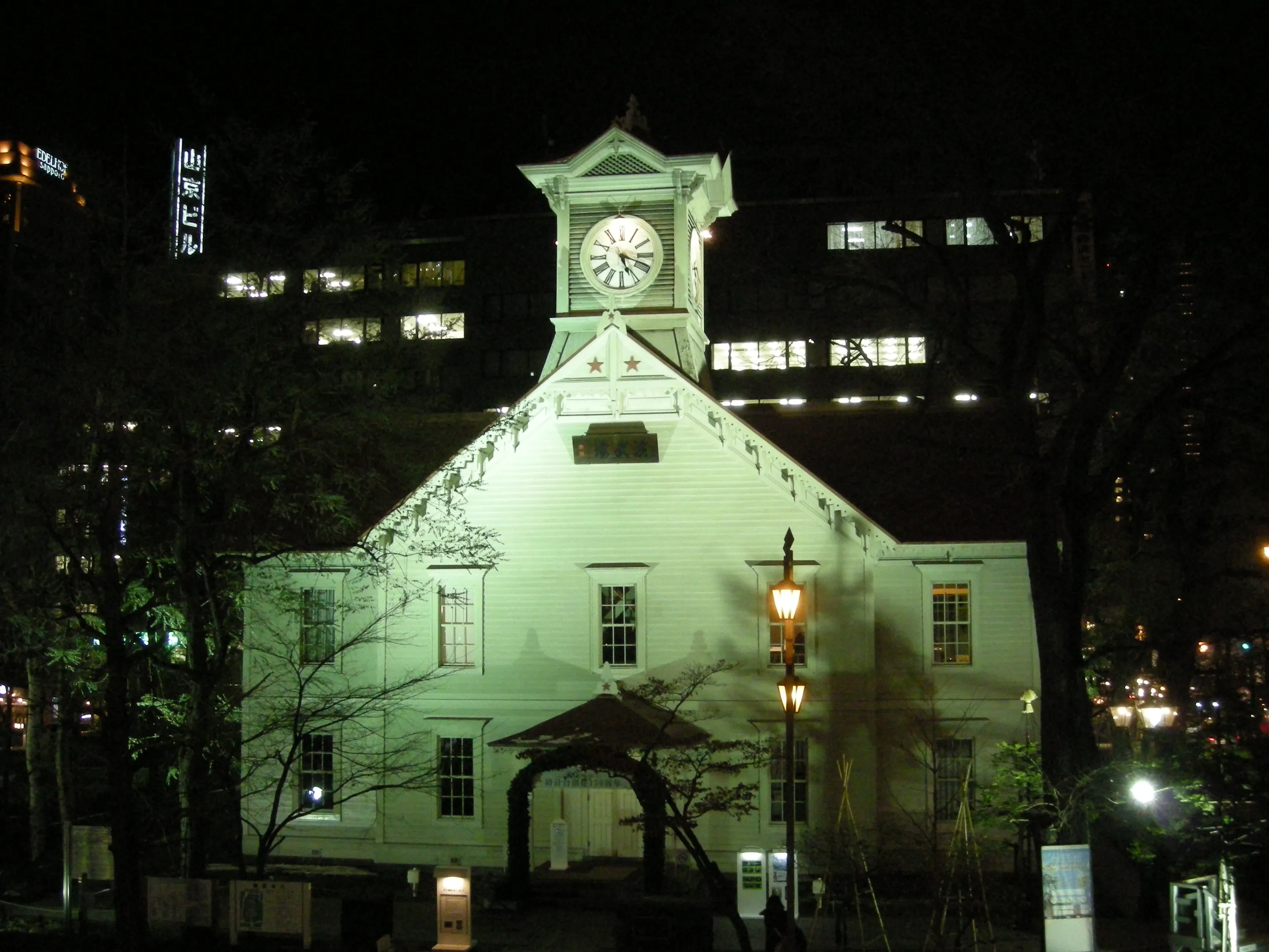 The Sapporo Clock Tower illuminated at night with its clock face glowing