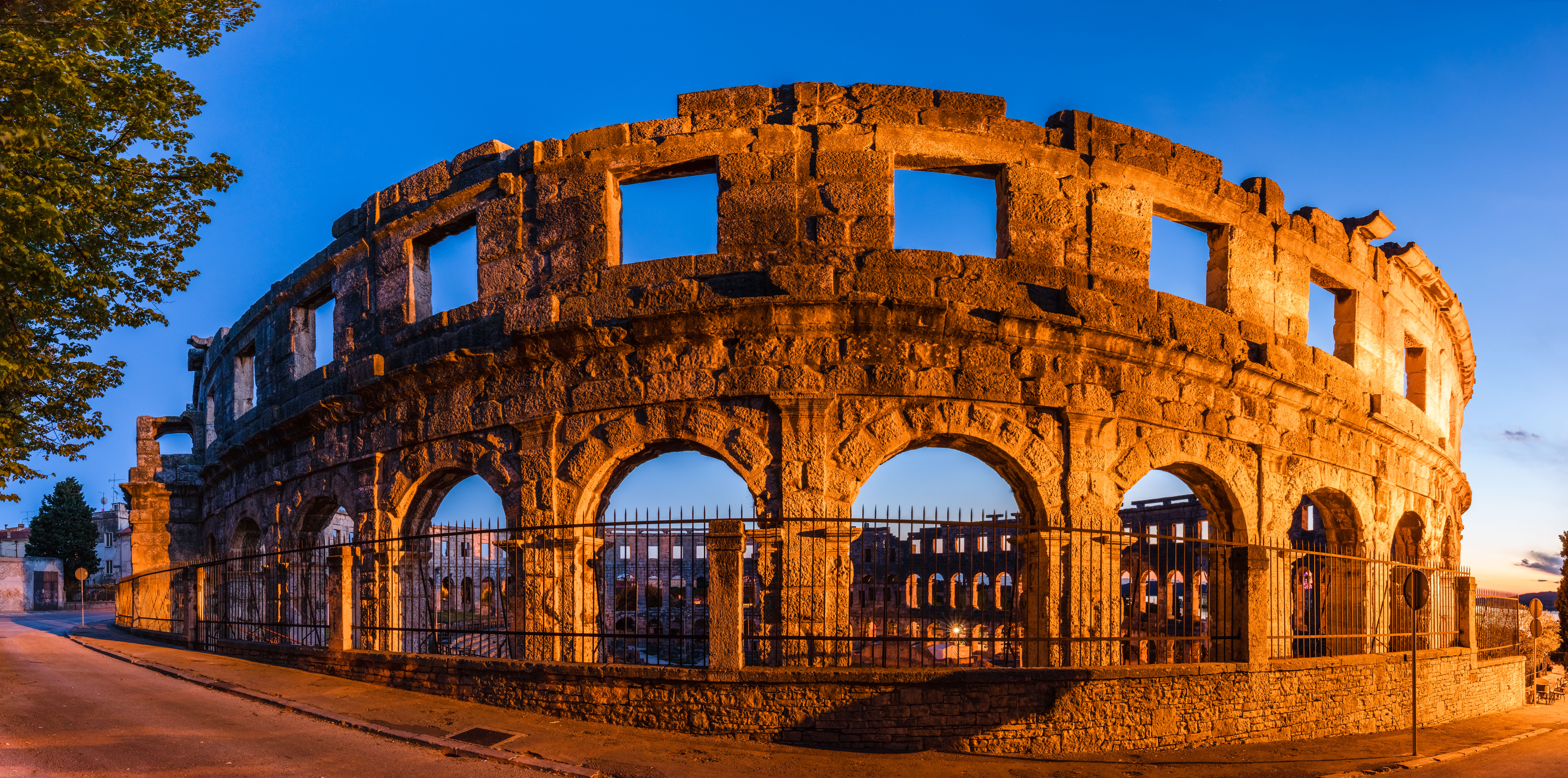 Pula Arena at dusk, the magnificent Roman amphitheatre in Pula, Croatia Pula Arena at sunset, the Roman amphitheatre's 2,000-year-old three-tiered stone arches glowing in warm light above the Istrian harbour town