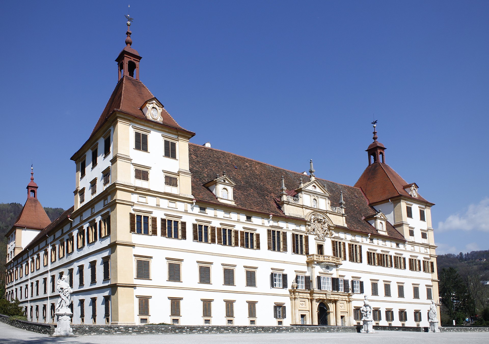 Front facade of Eggenberg Palace in Graz, a grand baroque palace with symmetric wings and a central tower set in parkland