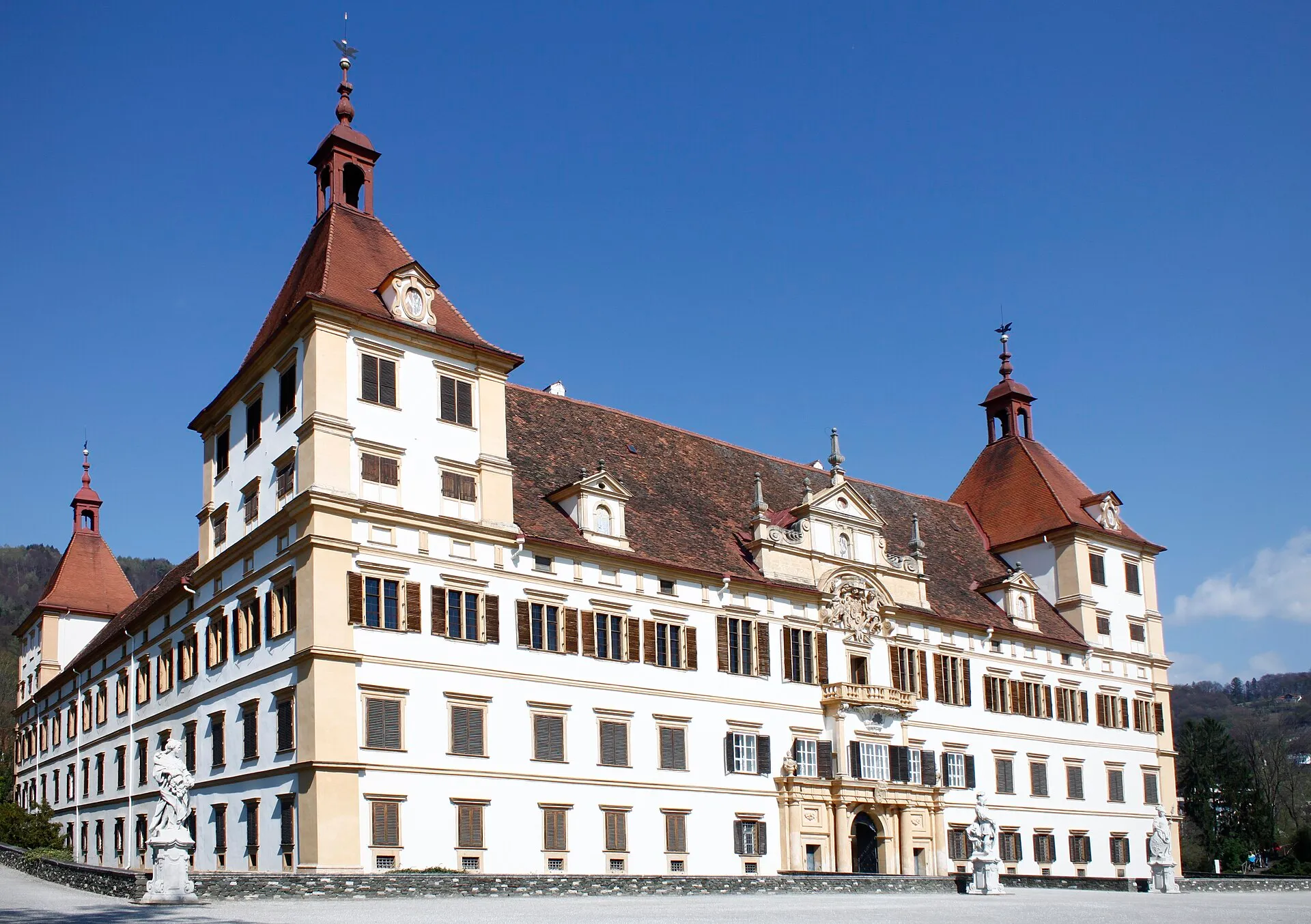 Front facade of Eggenberg Palace in Graz, a grand baroque palace with symmetric wings and a central tower set in parkland