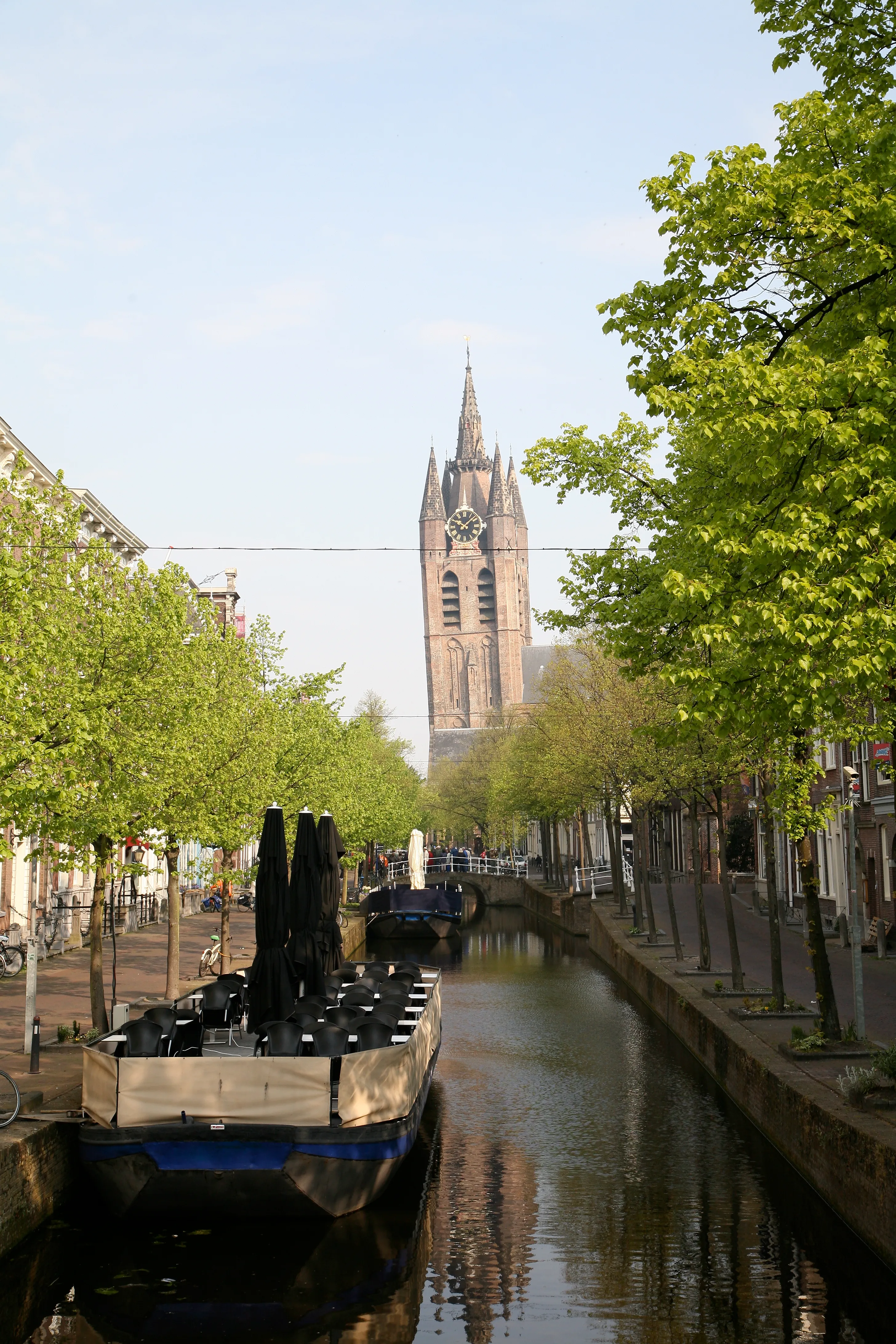 The leaning brick tower of the Oude Kerk in Delft seen from across the canal
