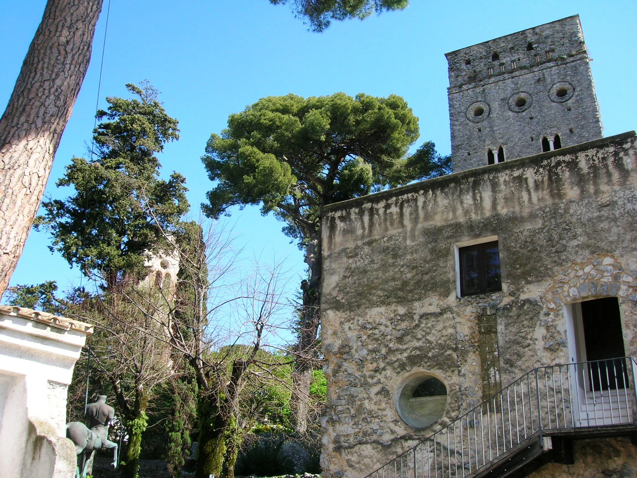 The medieval stone tower of Villa Rufolo rising above the villa's walls and pines in Ravello