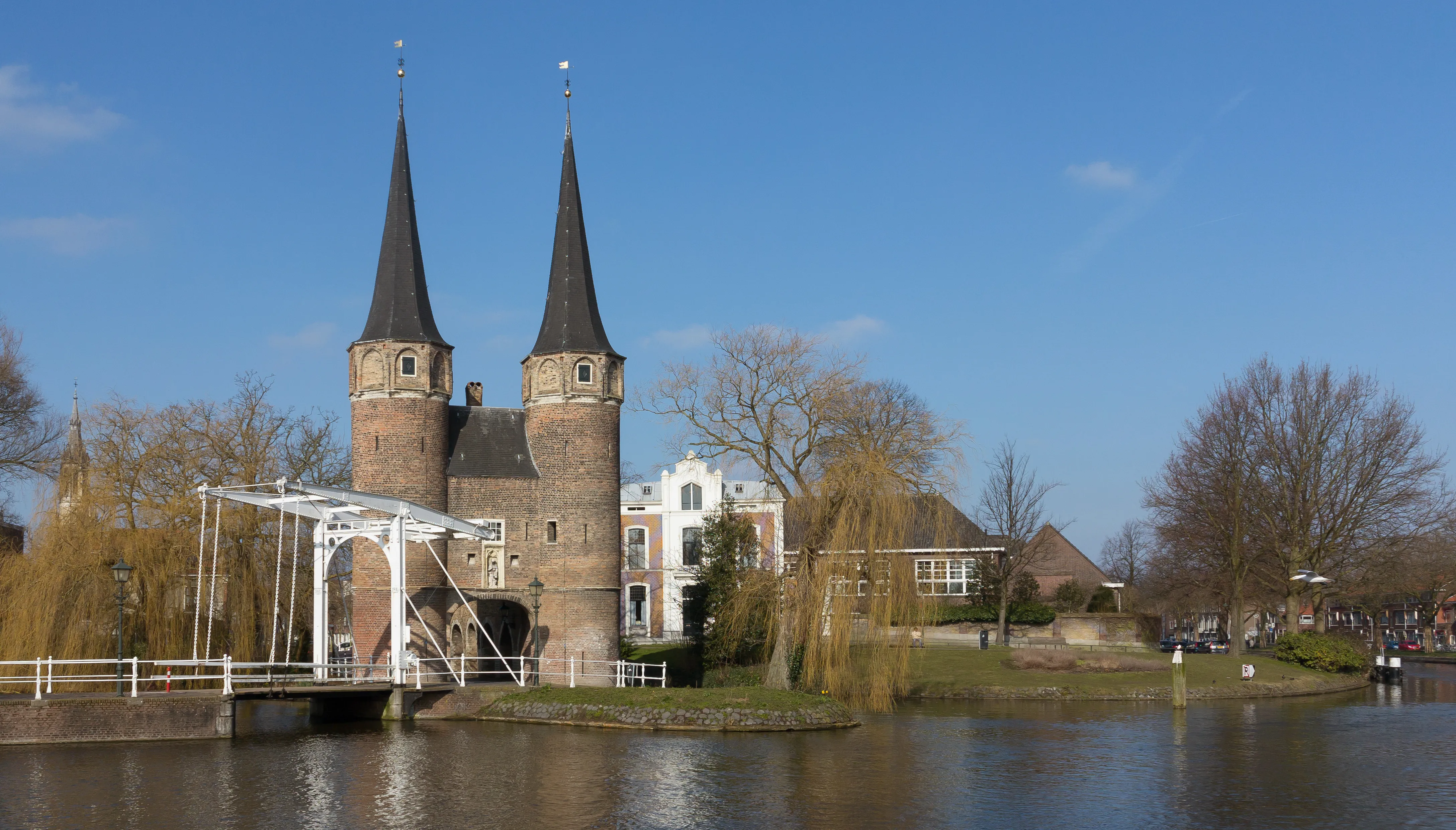 The twin spired towers of the Oostpoort gate in Delft reflected in the canal