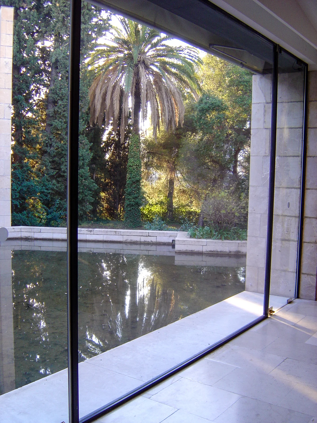 Full-height glass wall inside the Marc Chagall museum looking onto a reflecting pool and garden