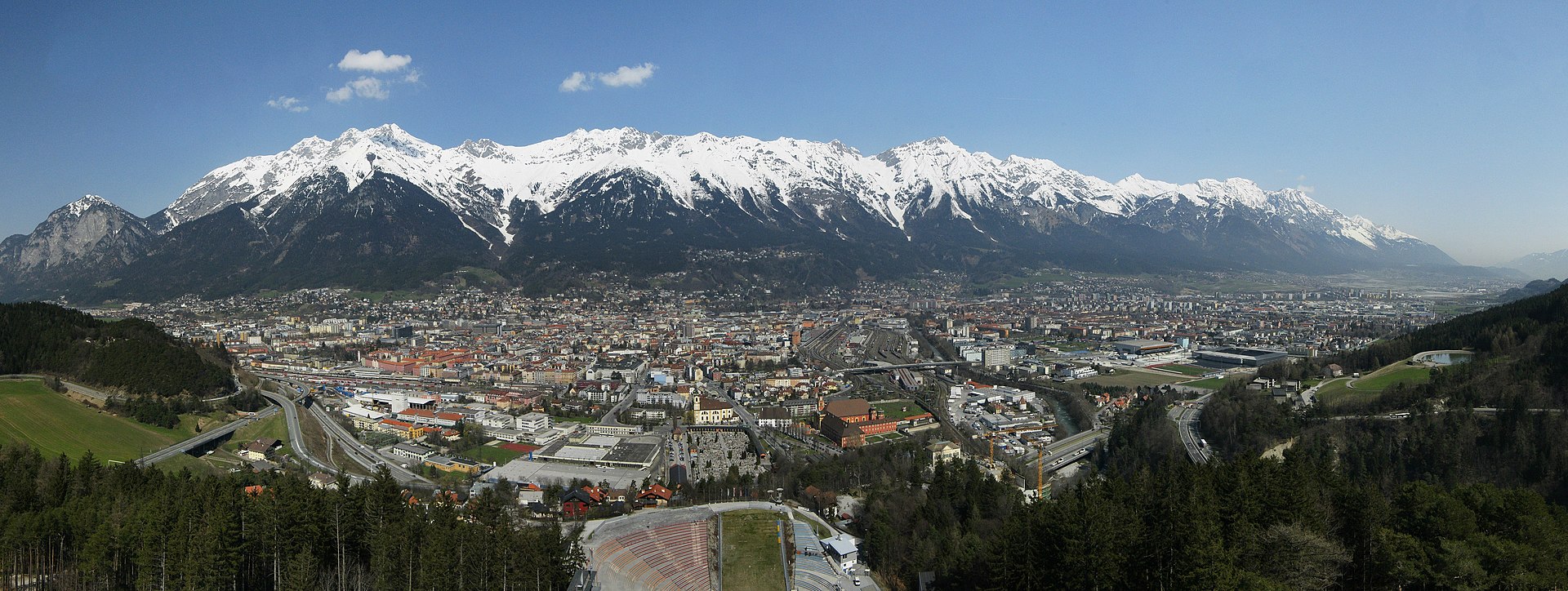 Panoramic view of Innsbruck's old town with colorful buildings along the Inn River backed by the snow-capped Nordkette mountain range