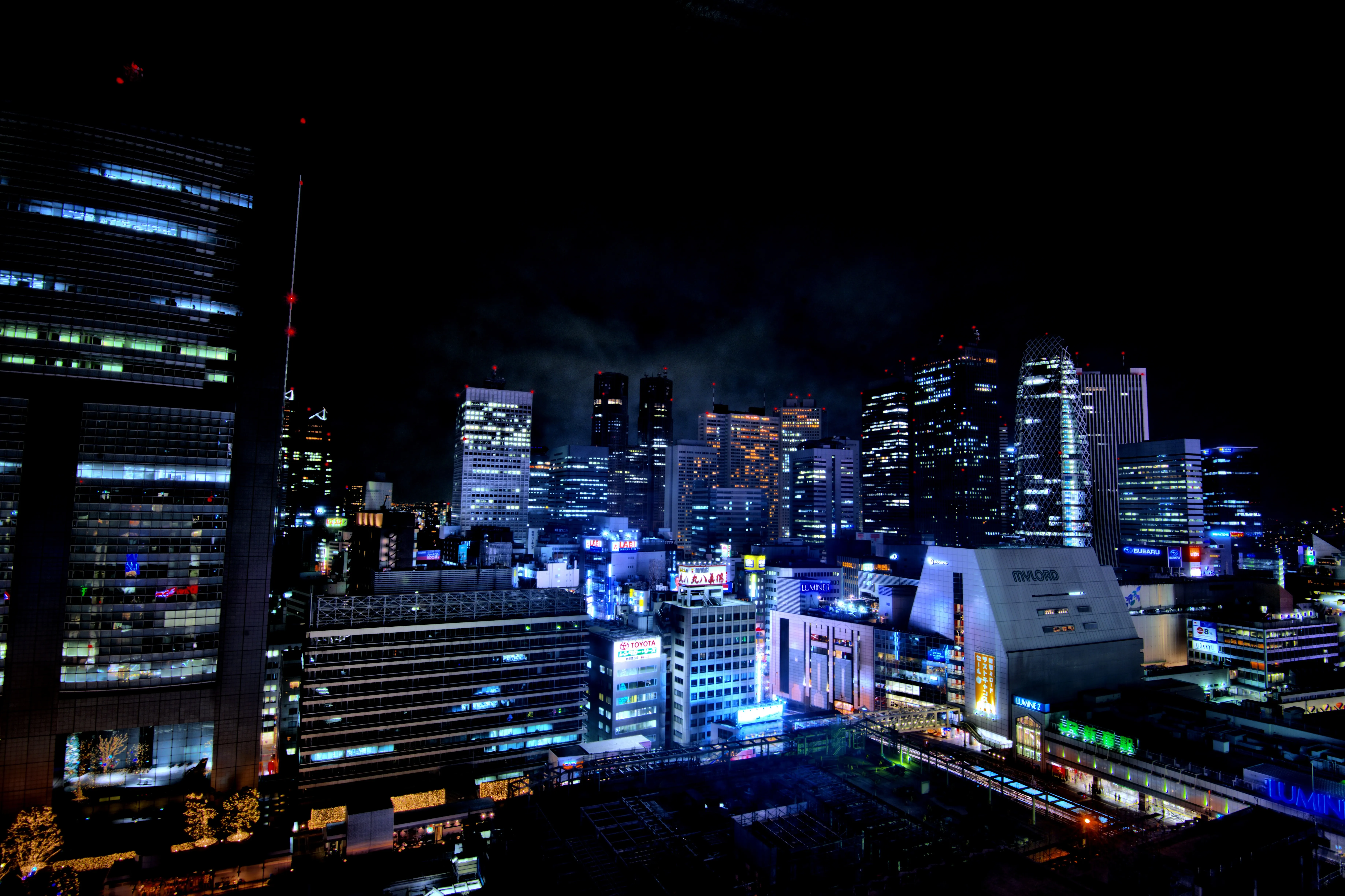 Neon signs and busy streets around the south entrance of Shinjuku Station at night