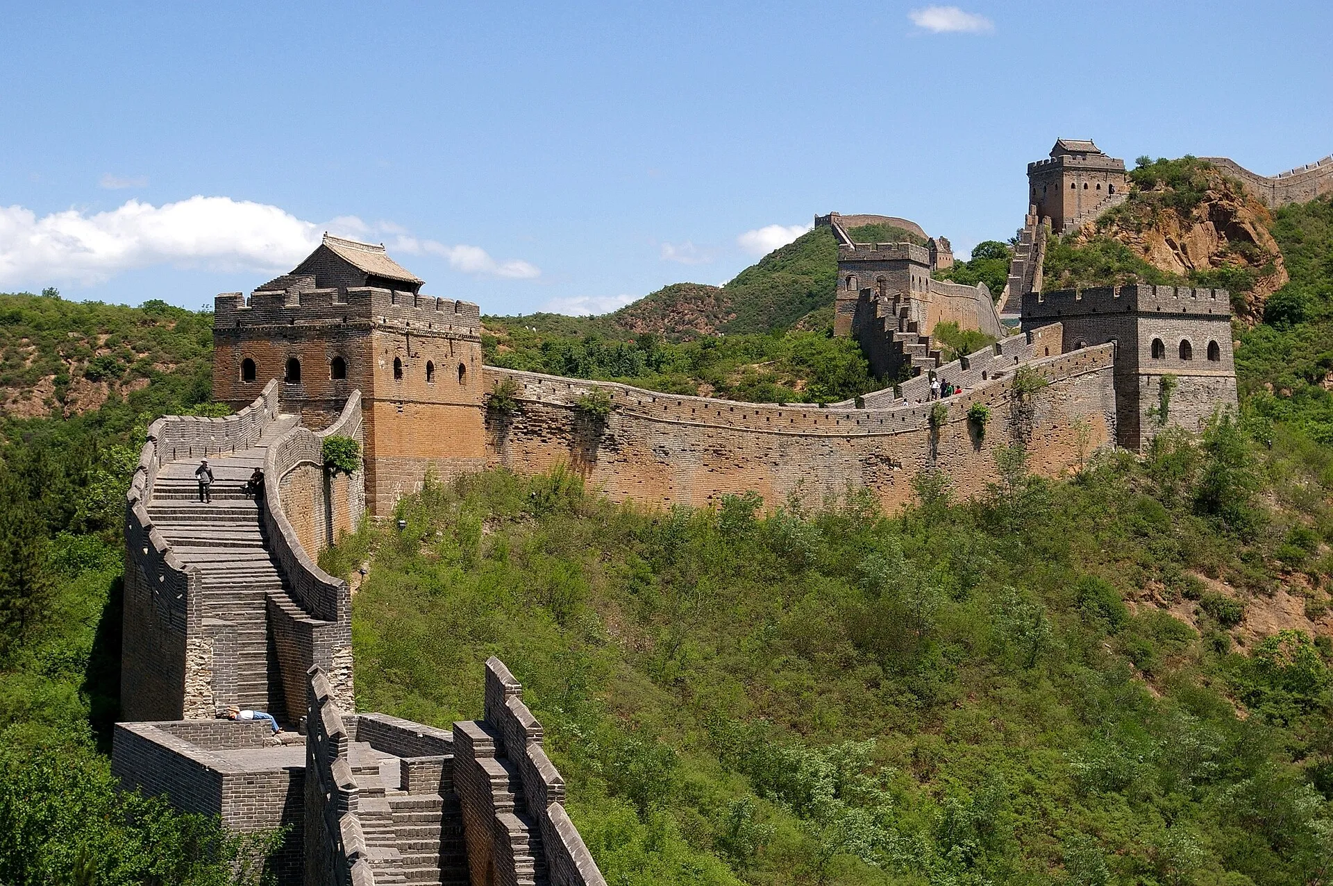The Great Wall of China winding through green mountain ridges