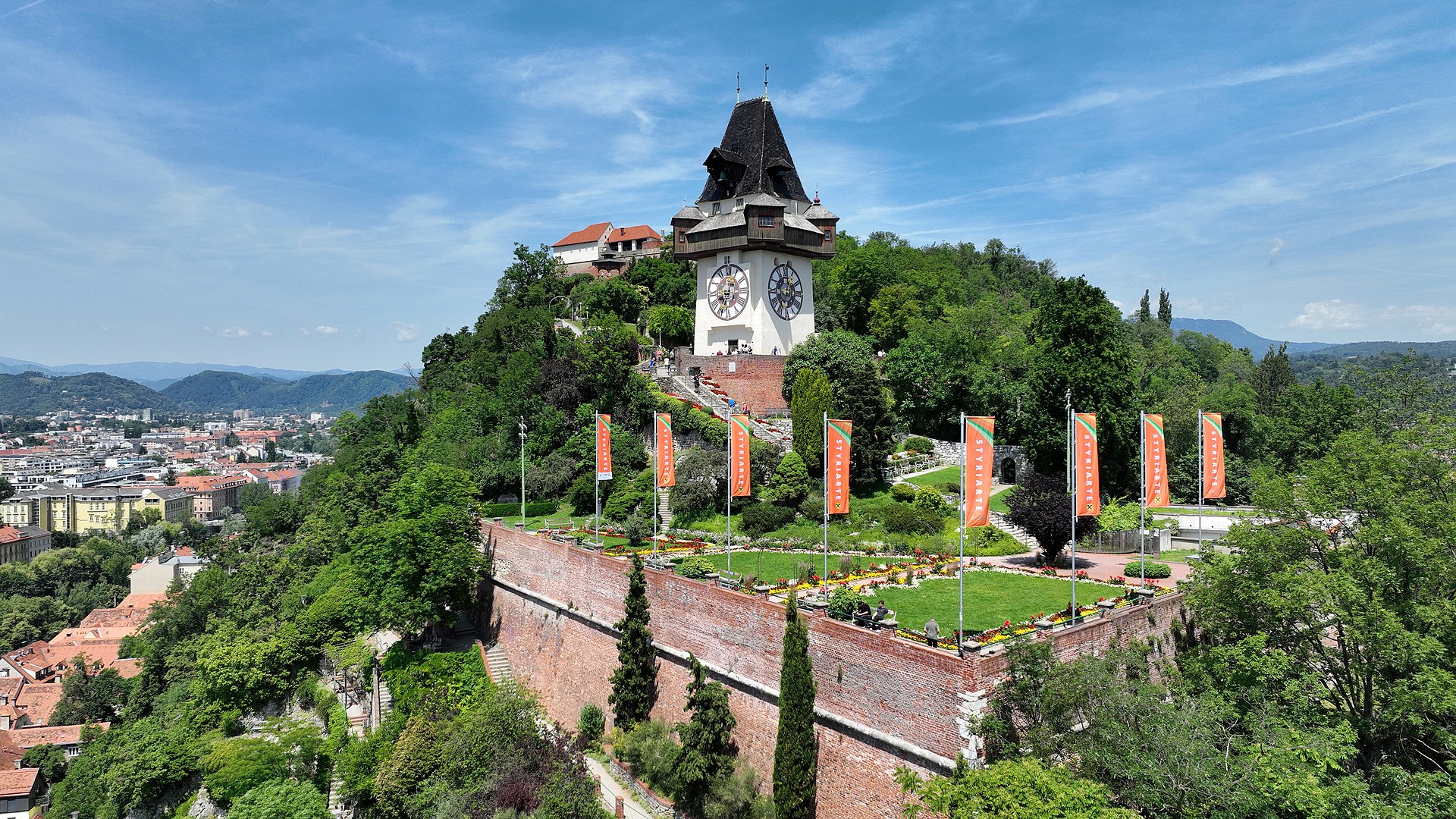 The Schlossberg hill rising above Graz's old town with the iconic Uhrturm clock tower at its summit surrounded by historic red-roofed buildings