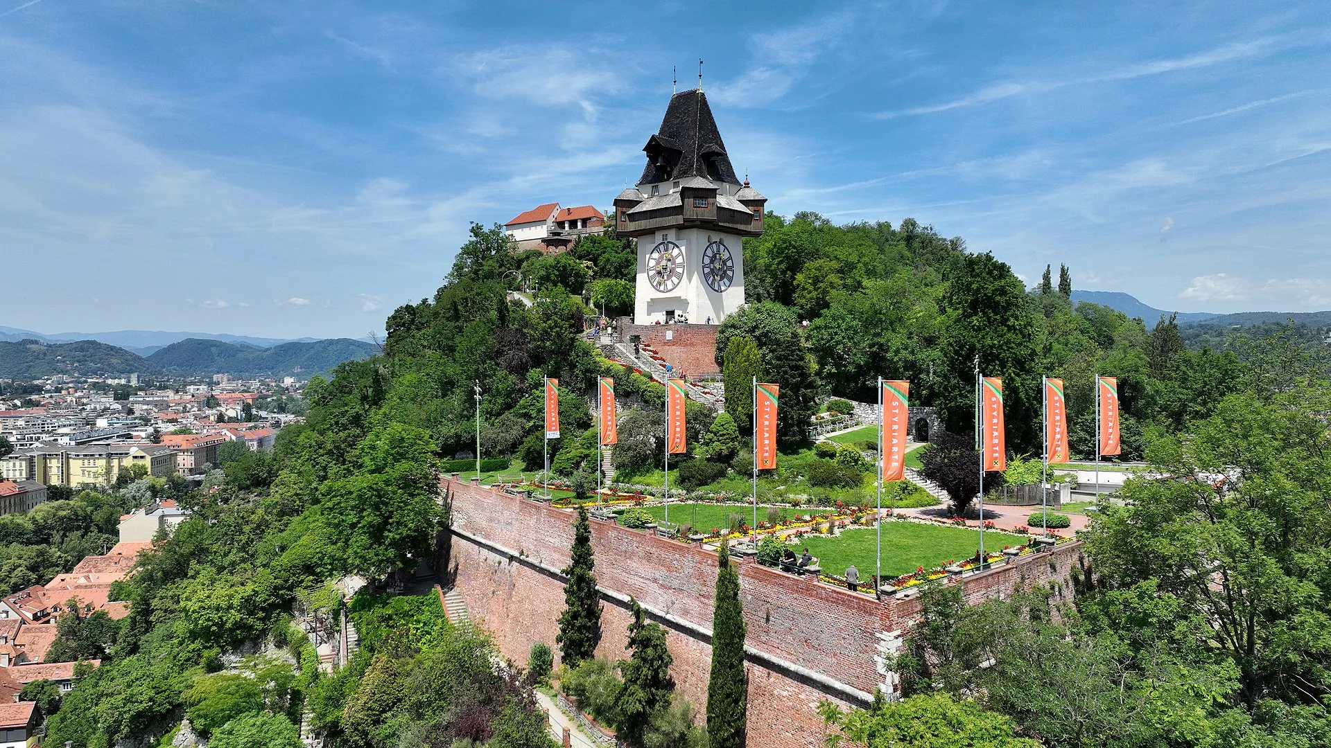 The Schlossberg hill above Graz's old town, the Uhrturm clock tower at its summit amid historic red-roofed buildings