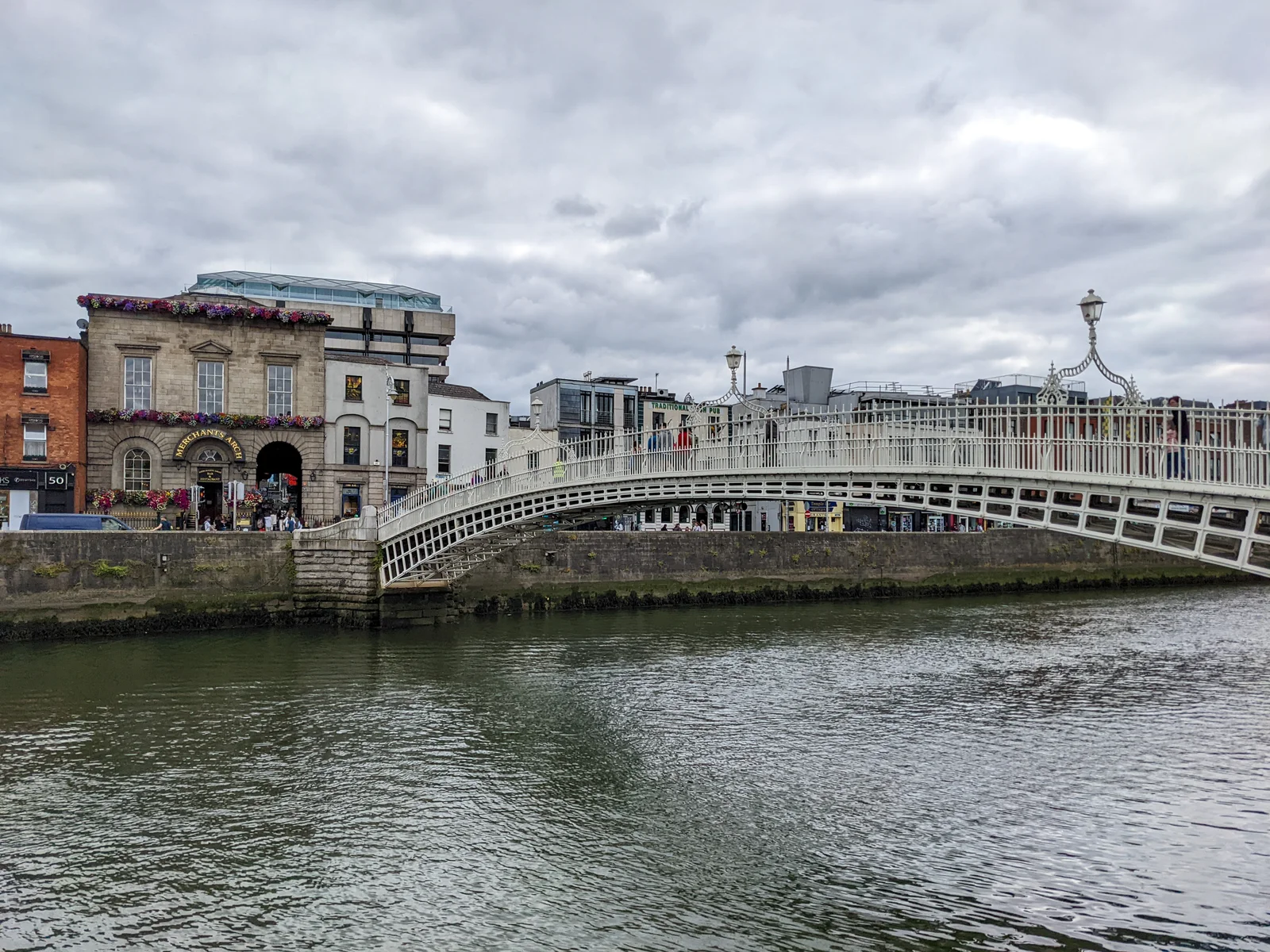 The white cast-iron Ha'penny Bridge arching over the River Liffey in Dublin, with Georgian quays behind