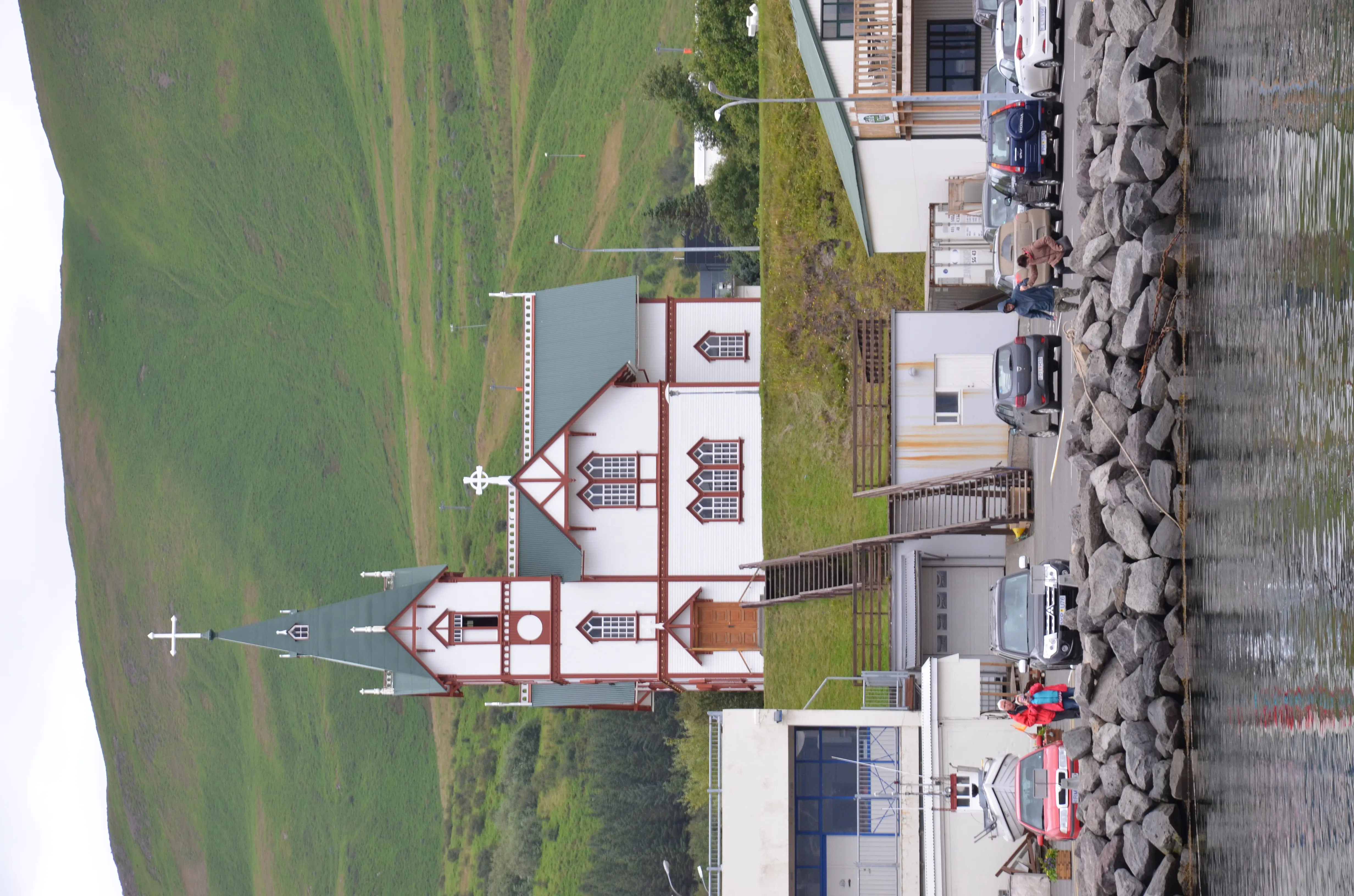 The white-and-red timber church of Húsavíkurkirkja with its tall octagonal spire under a clear northern Iceland sky
