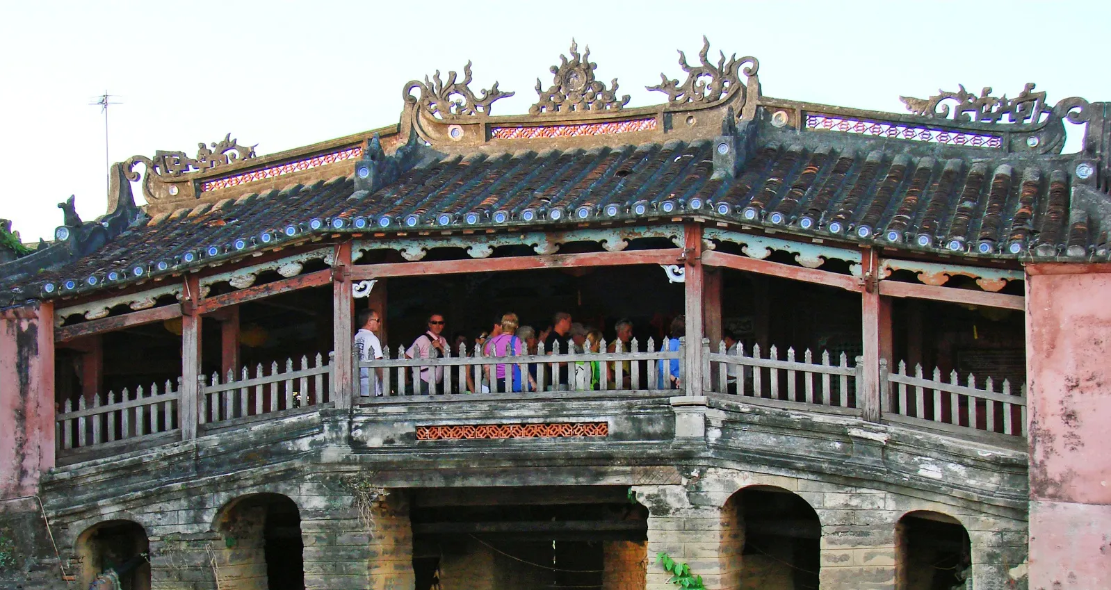 The Japanese Covered Bridge (Lai Vien Kieu) spanning a narrow canal in Hoi An Ancient Town, with its distinctive wooden covered walkway and small temple visible at the entrance