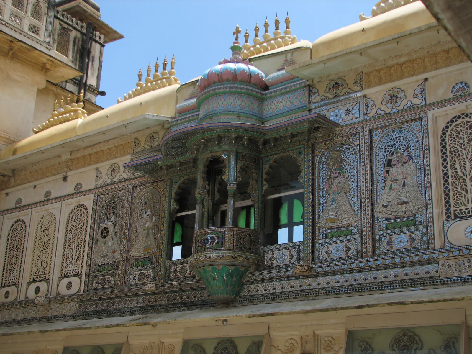 Close-up of colored glass, mirror, and gem inlay on a Mor Chowk wall inside City Palace Udaipur