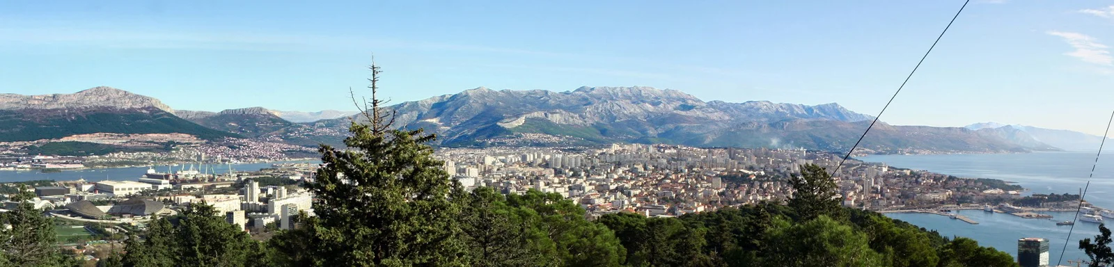 A wide panorama of Split's rooftops and harbour spread along the Adriatic coast, viewed from the top of Marjan hill