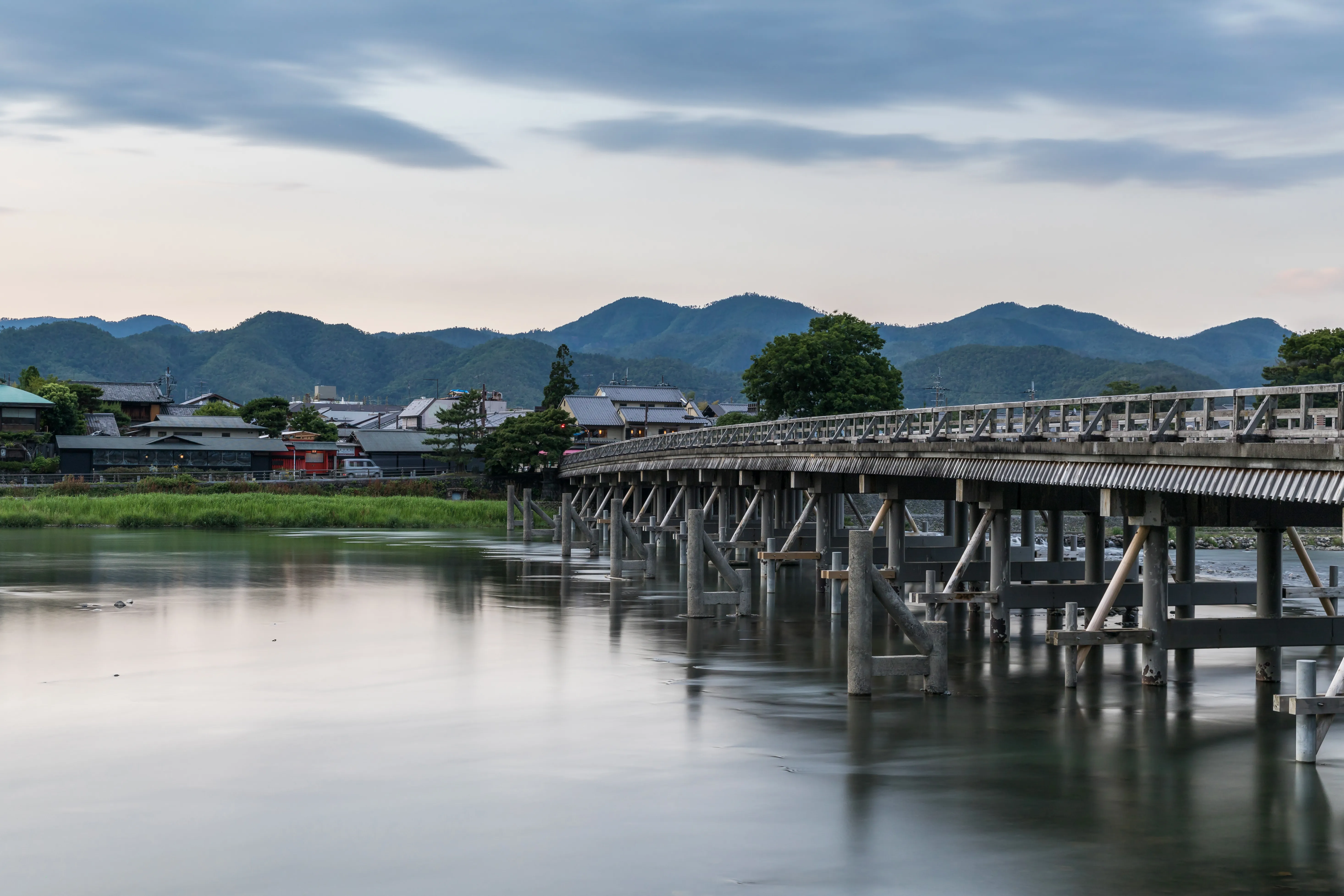 The wooden Togetsukyo Bridge spanning the Katsura River below the wooded hills of Arashiyama at dusk