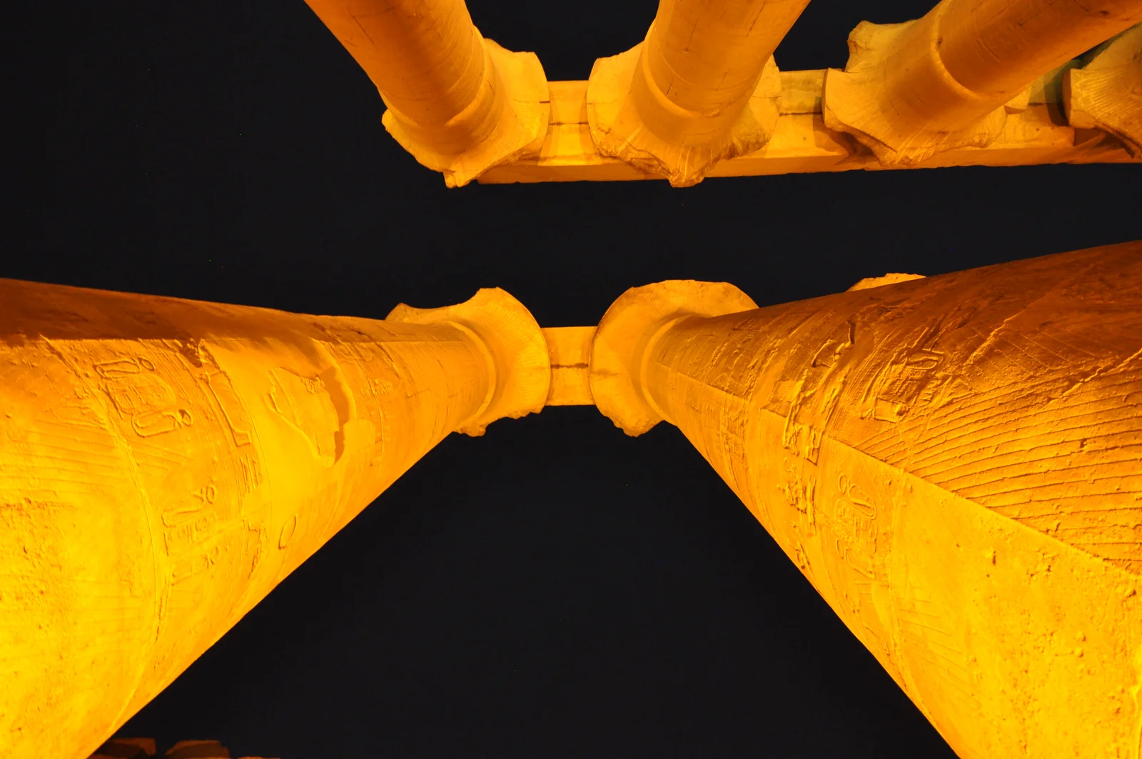 The colonnade and pylon of Luxor Temple floodlit against the evening sky