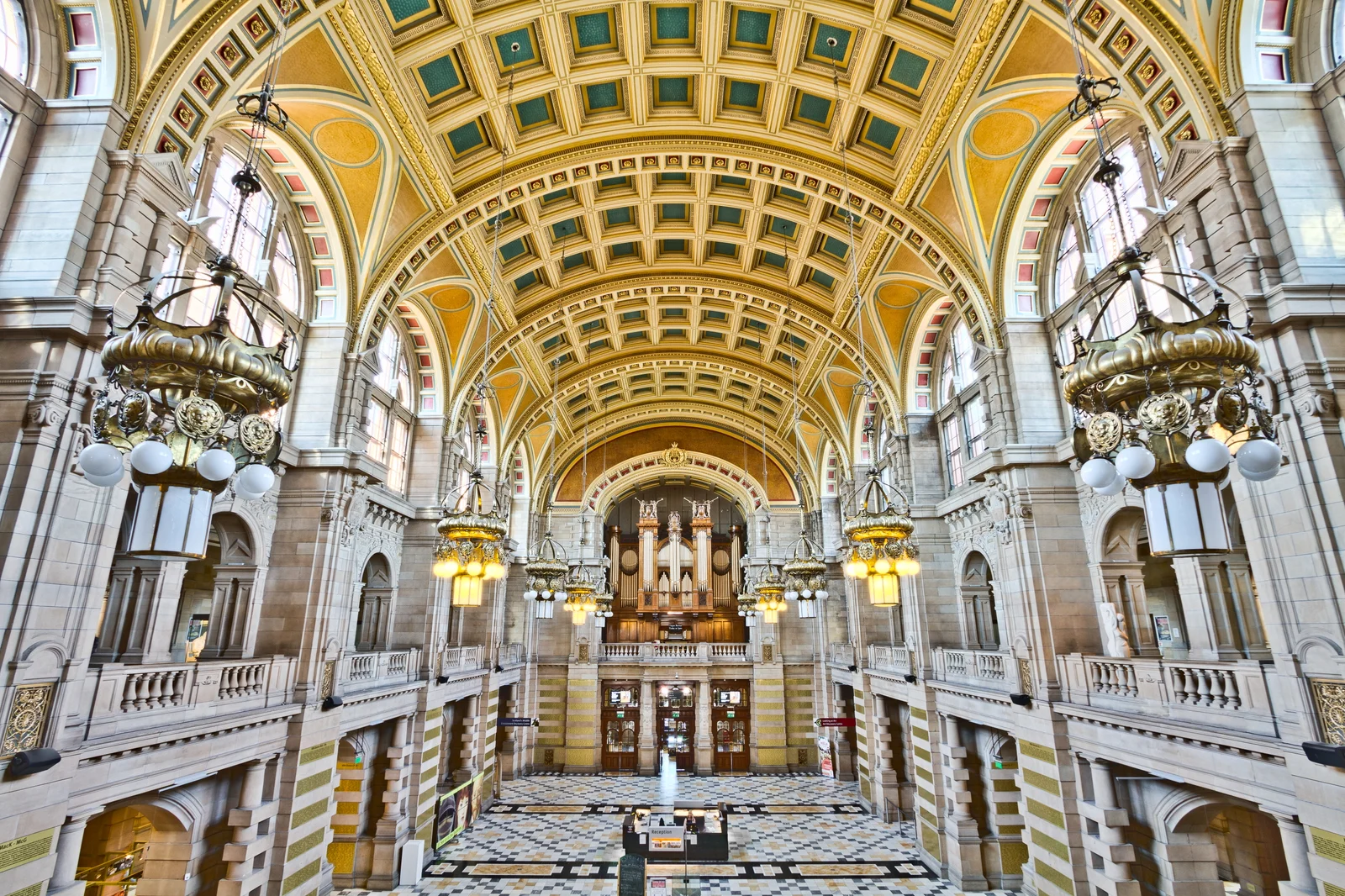 The barrel-vaulted Centre Hall of Kelvingrove, with a pipe organ on the far wall and ornate brass chandeliers hanging beneath the coffered ceiling