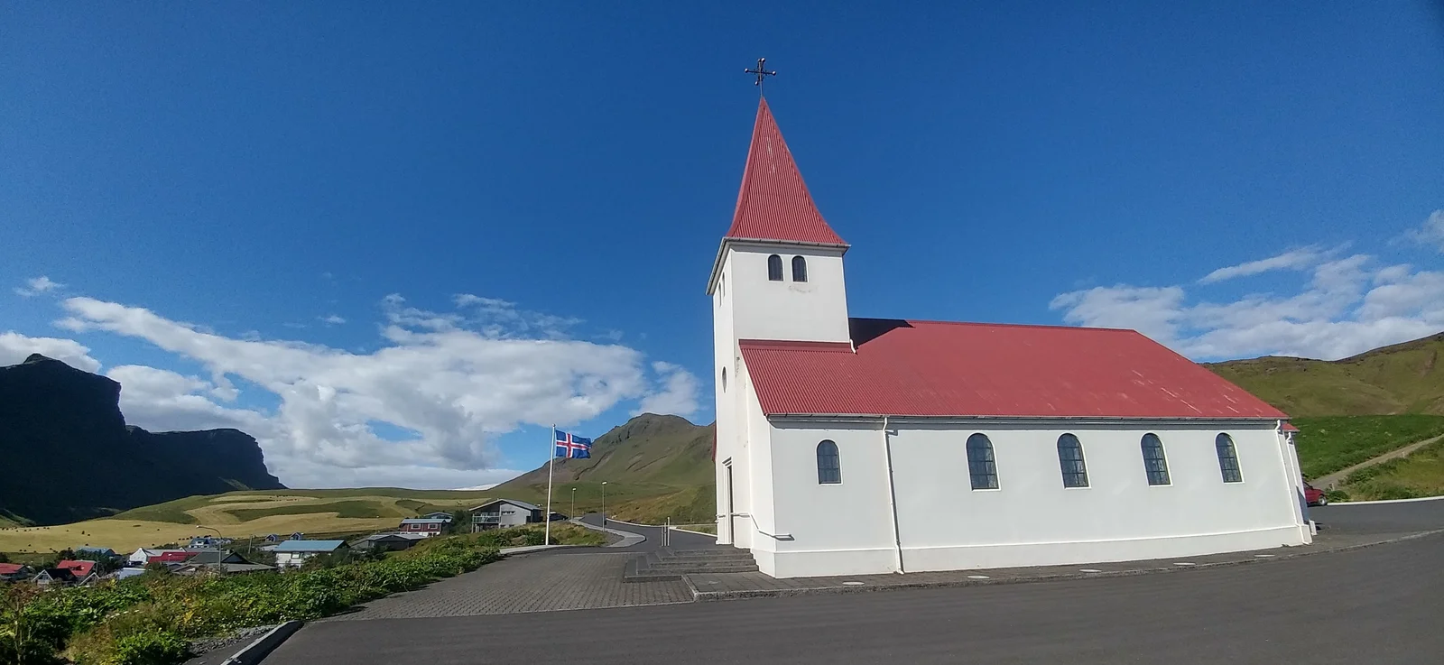 The white walls and red roof of Víkurkirkja church on its green hill above the village of Vík in south Iceland