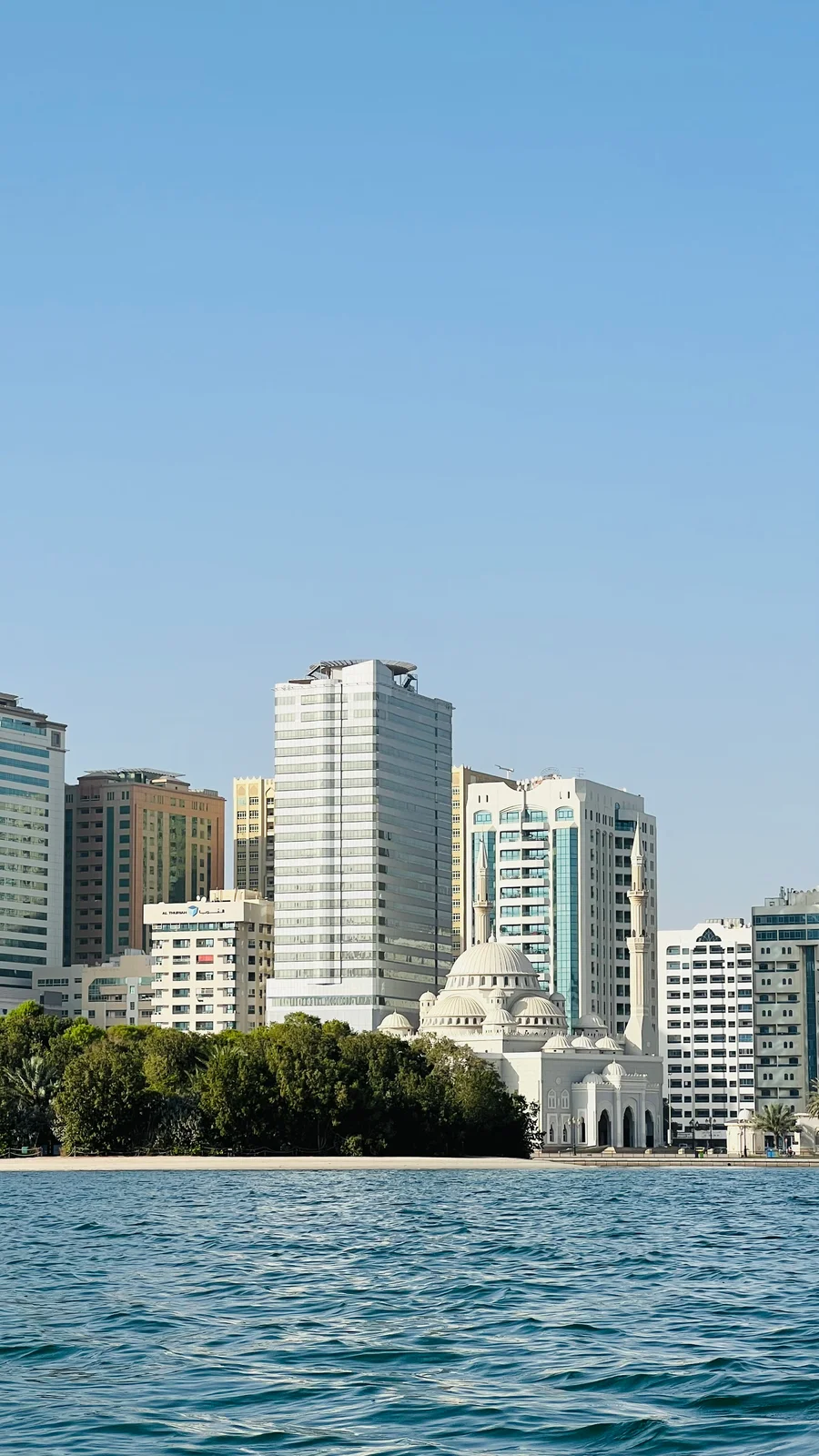 Al Noor Mosque's white domes and twin minarets seen across Khalid Lagoon in Sharjah