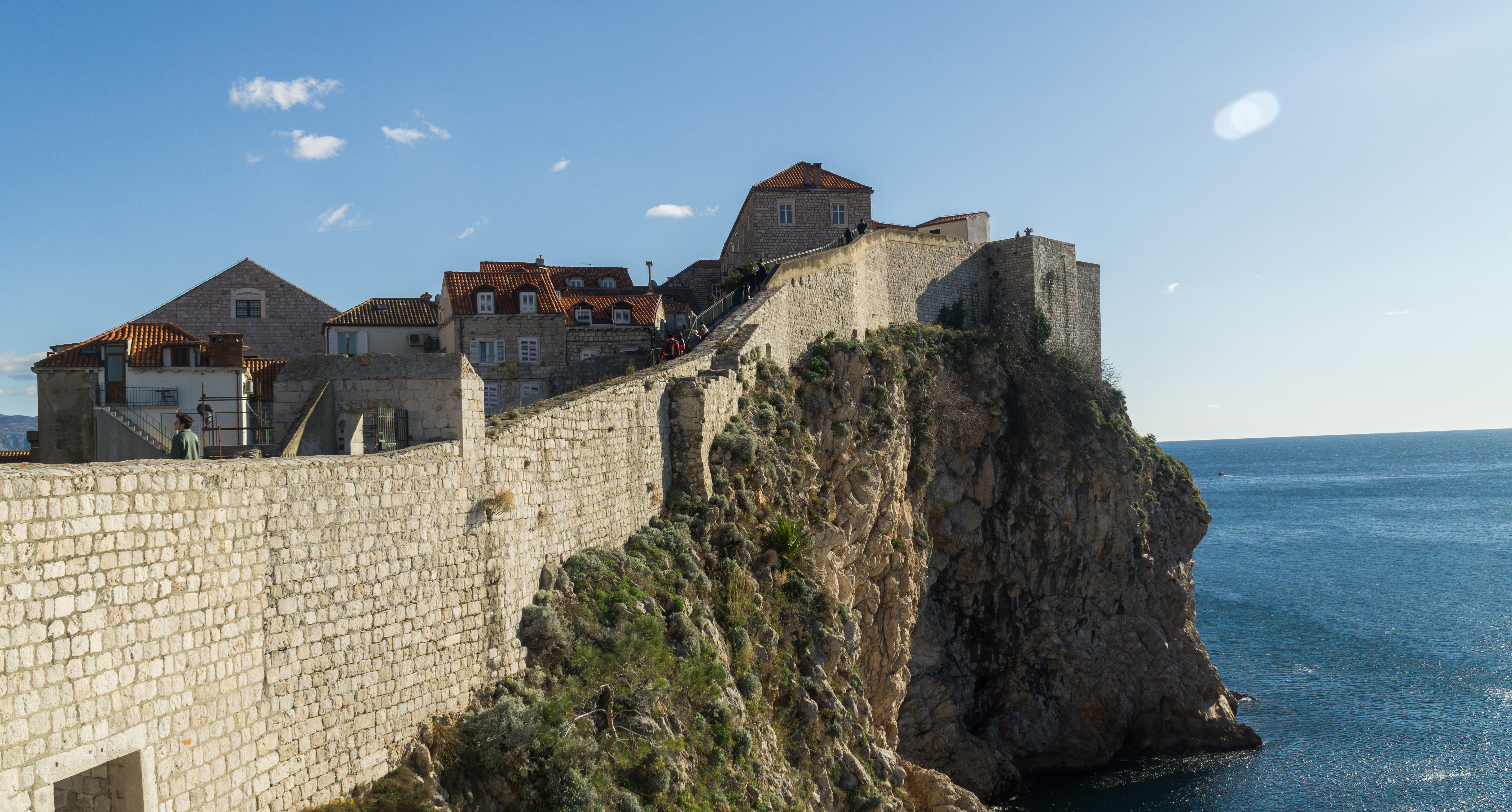 The city walls of Dubrovnik's old town rising above the Adriatic coast, Croatia