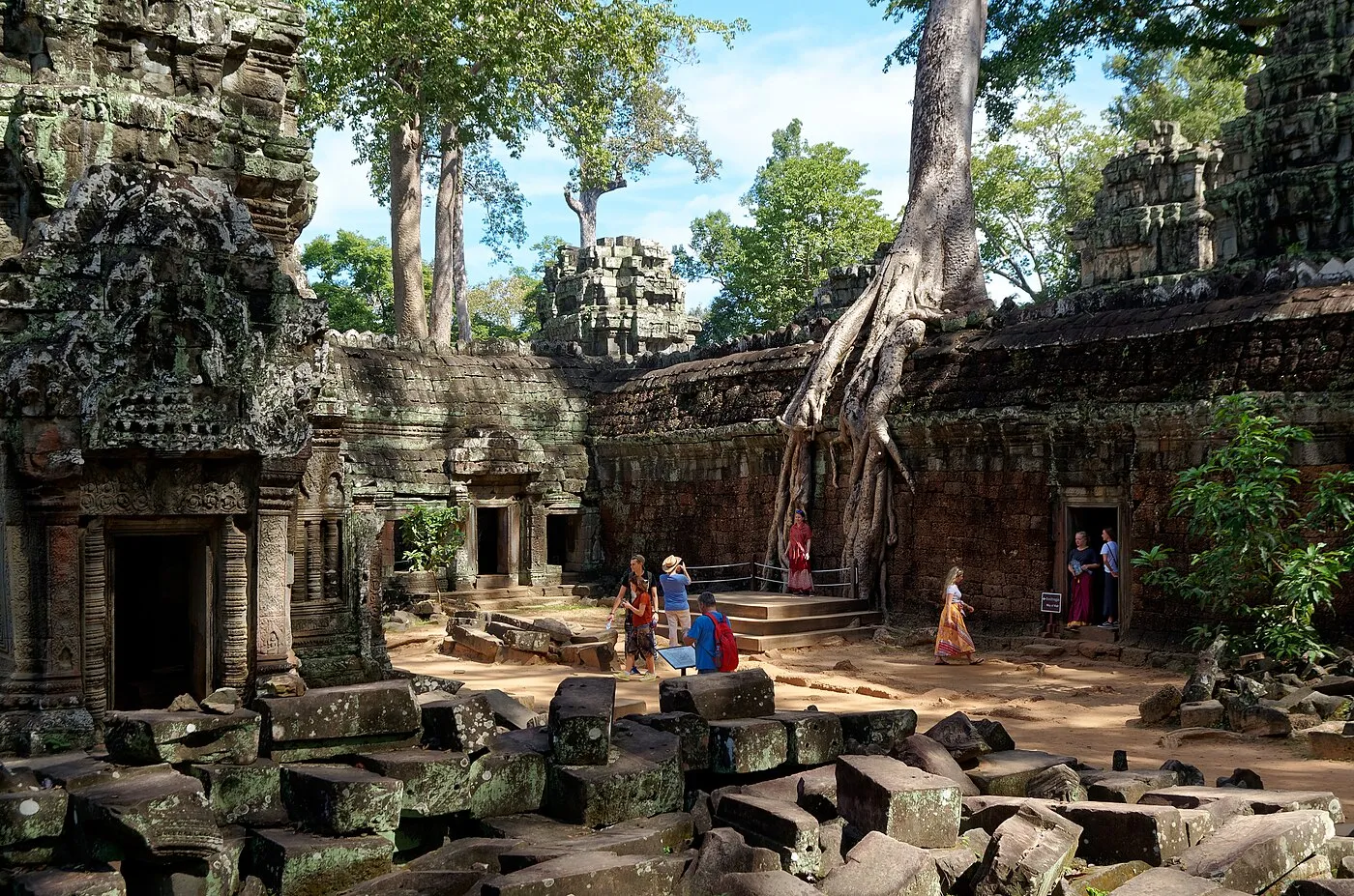 Ancient stone gallery at Ta Prohm with massive tree roots reclaiming the temple walls in Angkor, Cambodia