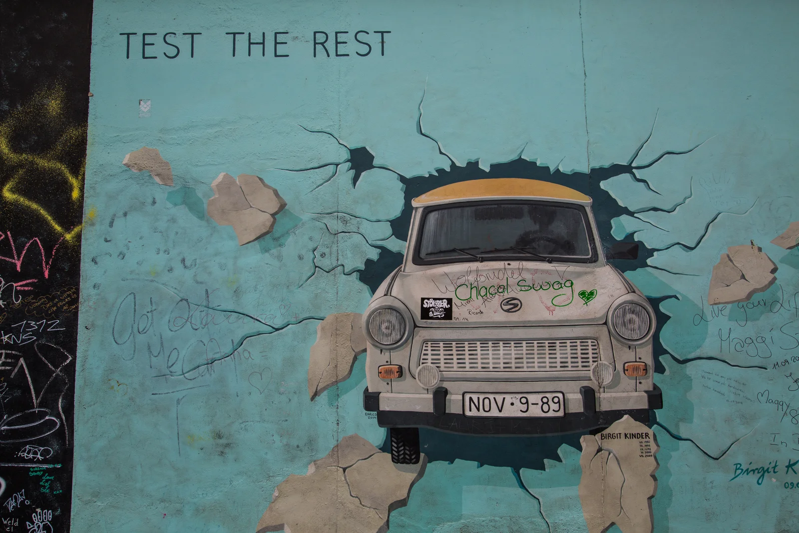 A painted Trabant car breaking through the concrete on the East Side Gallery of the Berlin Wall