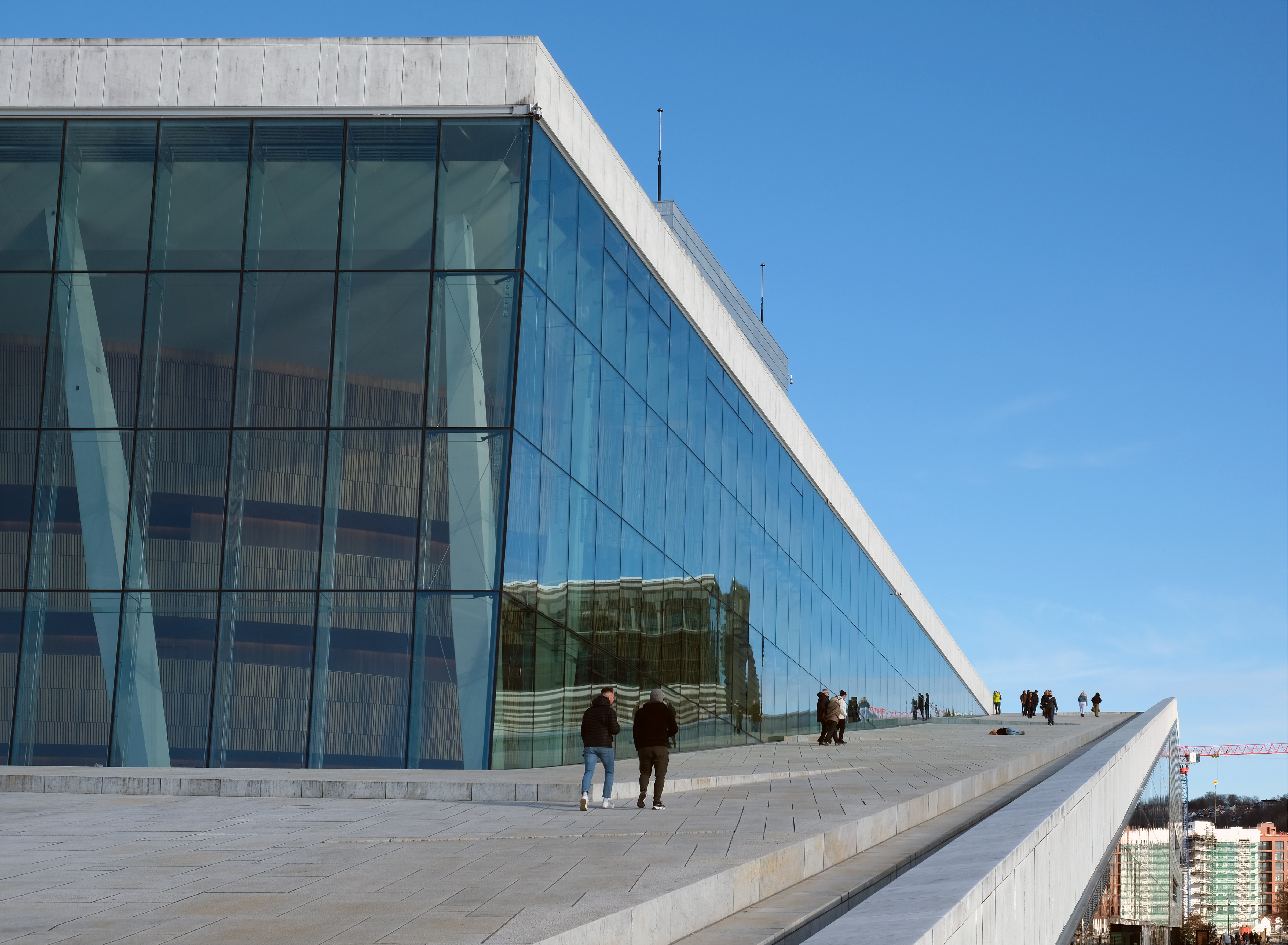 Oslo Opera House rising from the Oslofjord waterfront, its white marble roof sloping to the water