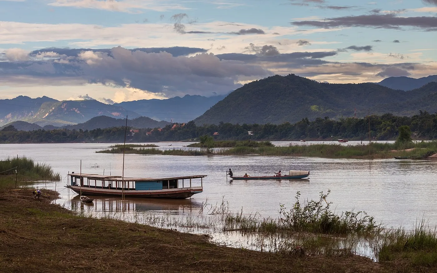 Pirogue and boats on the Mekong River at sunset with a colourful sky in Luang Prabang, Laos