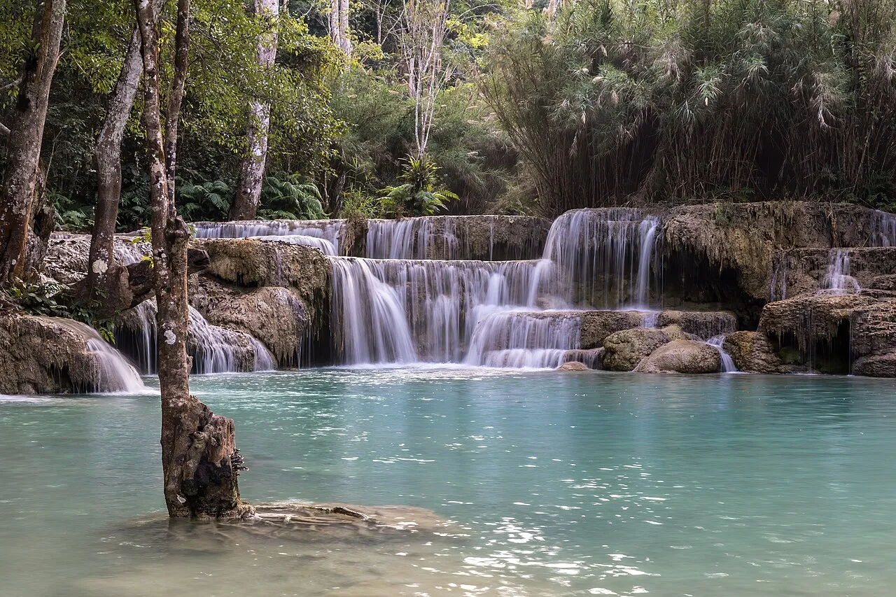 Turquoise tiered pools and waterfall cascading through jungle at Kuang Si near Luang Prabang, Laos